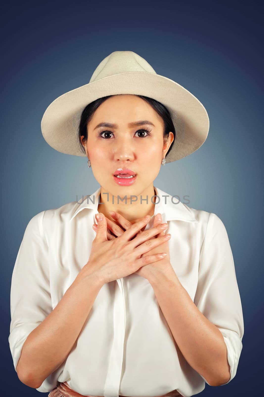 Shocked woman wearing stylish hat looking at camera and dark background