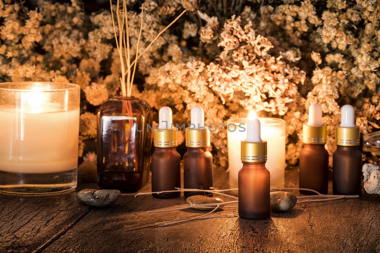 Bottles with organic essential aroma oil with dry flower on old wooden background.