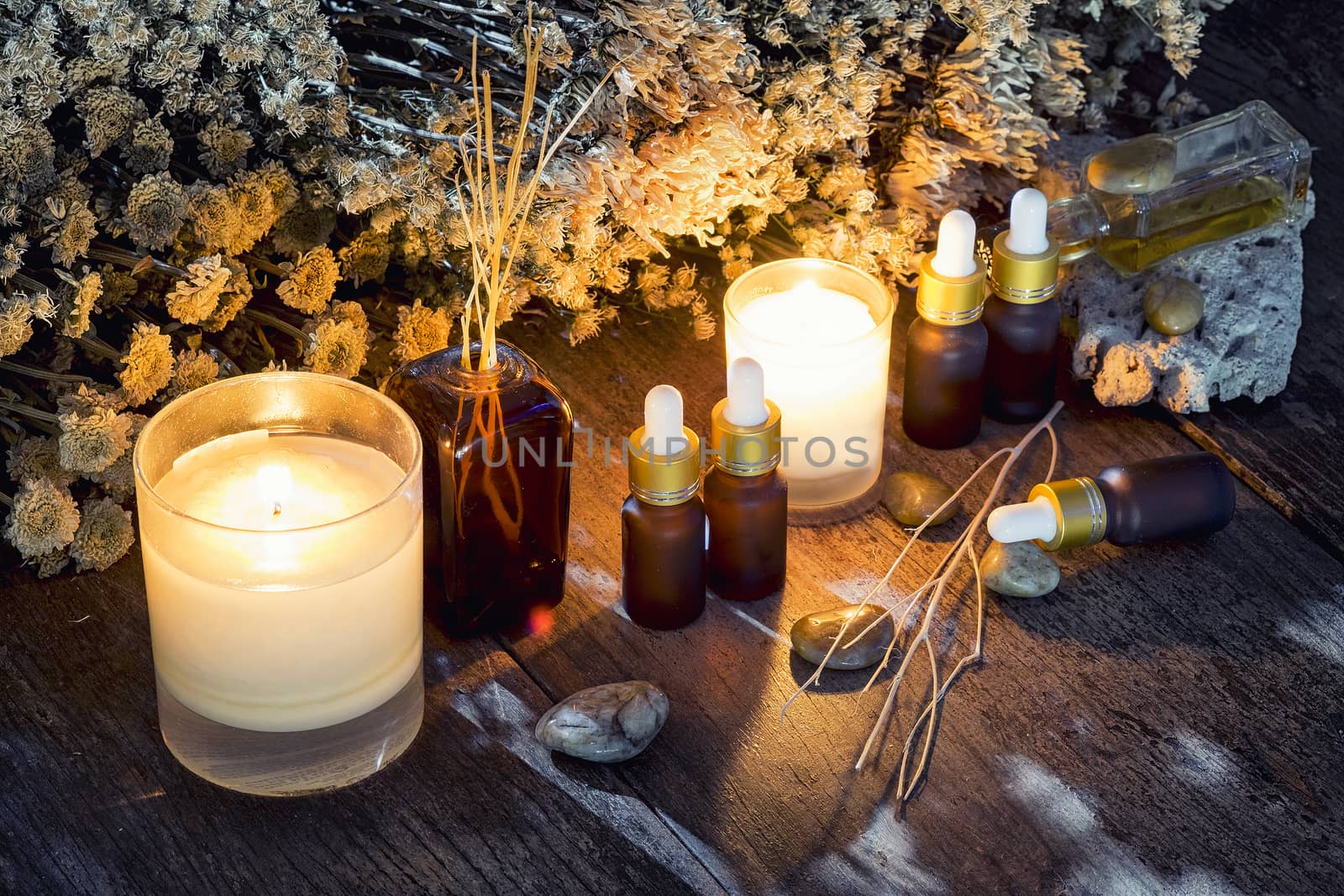 Bottles with organic essential aroma oil with dry flower on old wooden background.