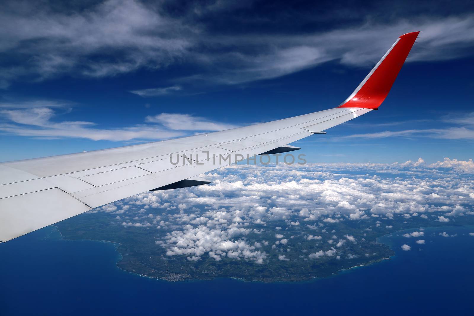 Aerial view from the plane over Punta Cana, Dominican Republic. Flying above the clouds. Wing of an airplane flying above the Atlantic Ocean.