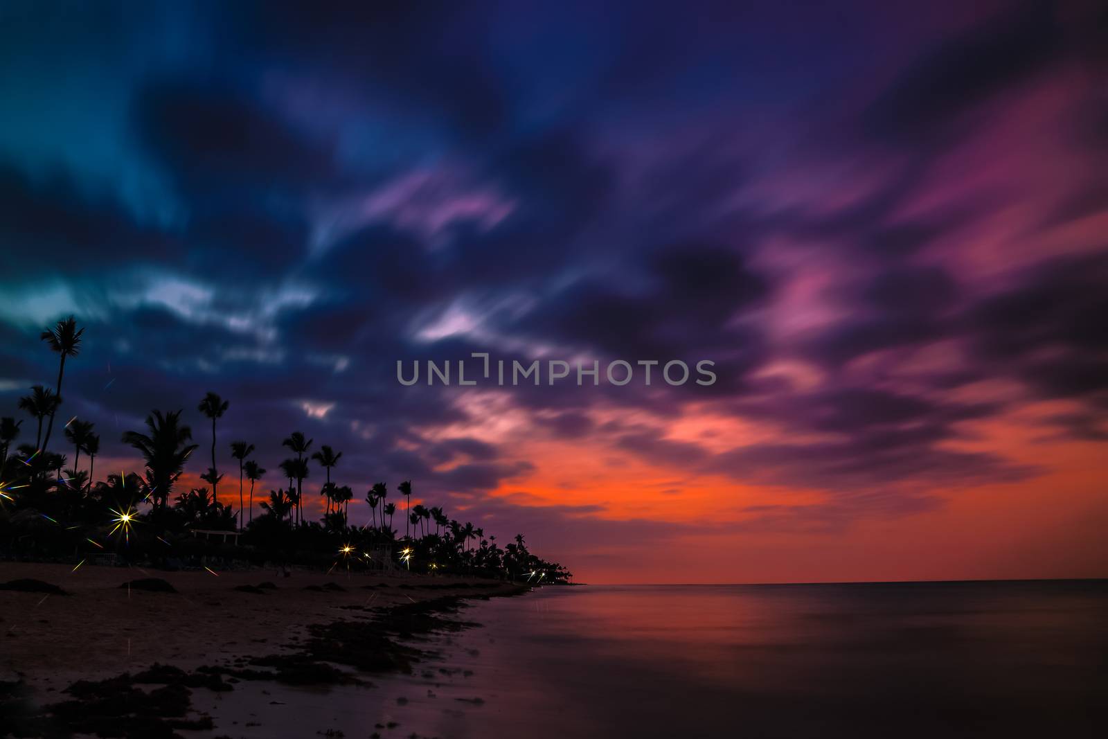 Dramatic sunset over the exotic beach, with palms. Incredible sunset on a tropical island in the ocean. Colorful dramatic sky with sunset.
