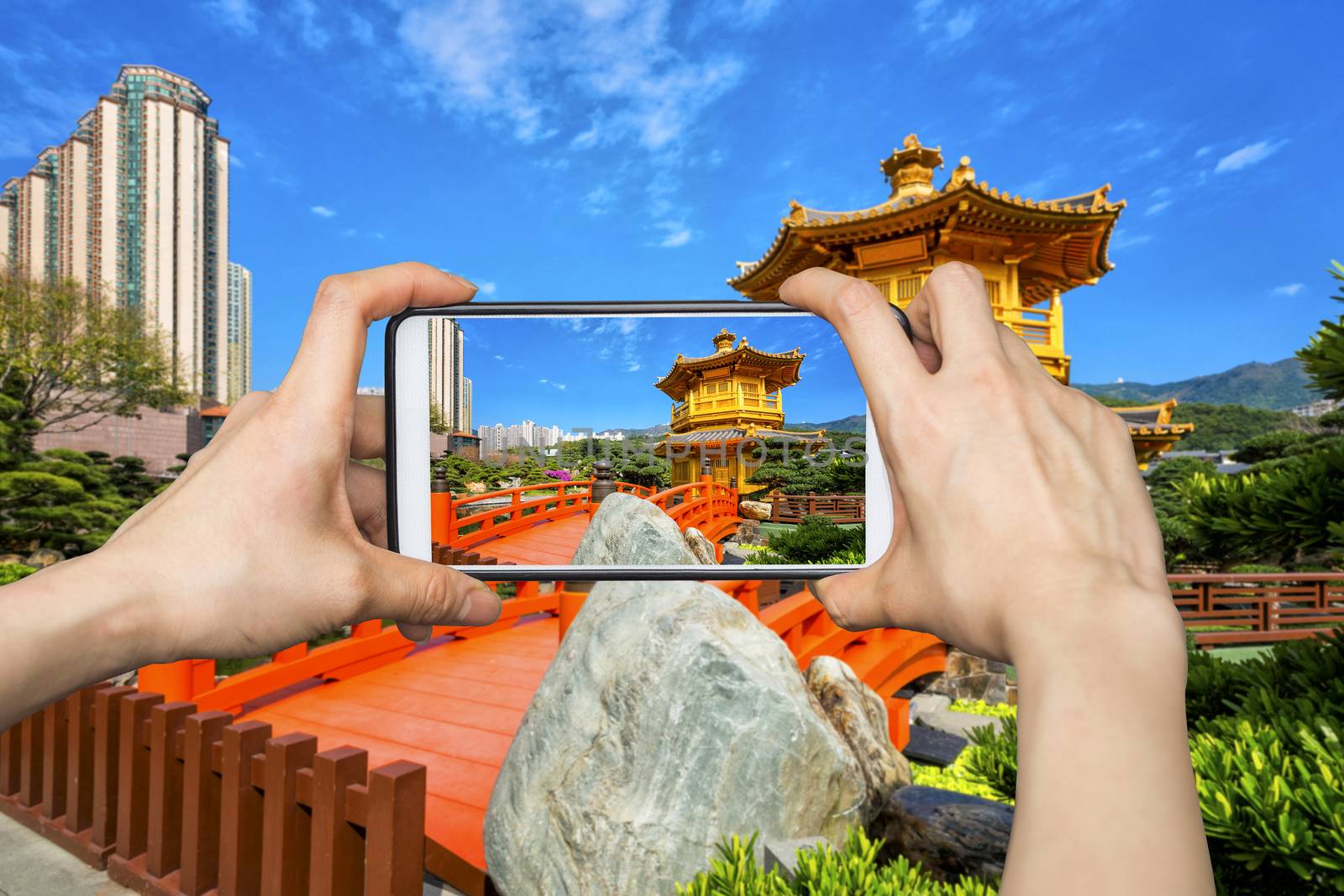 Girl taking pictures on mobile smart phone in Front View The Golden Pavilion Temple in Nan Lian Garden