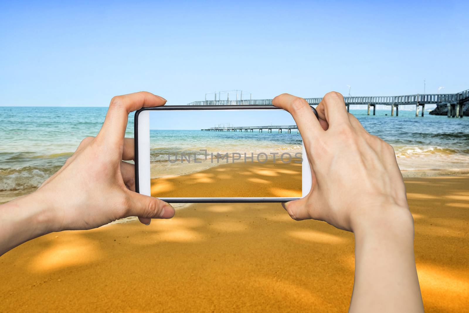 Girl taking pictures on mobile smart phone in Wave on the sand beach