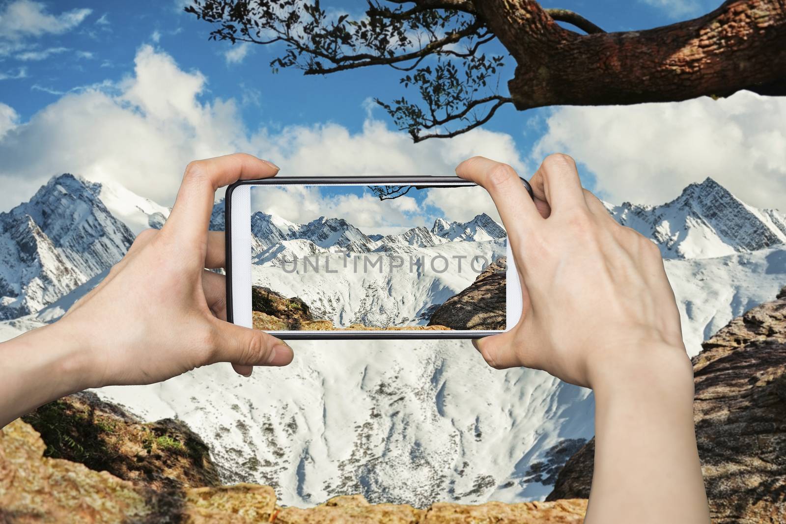 Girl taking pictures on mobile smart phone in High snow mountain by Surasak