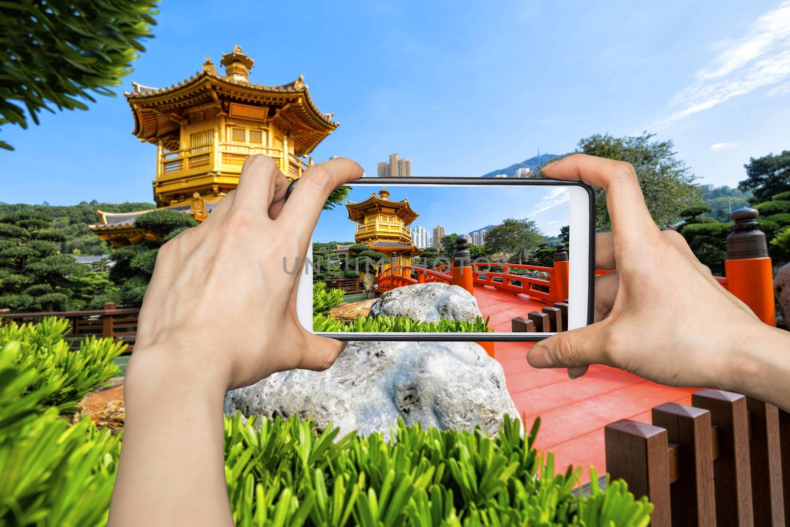 Girl taking pictures on mobile smart phone in Front View The Golden Pavilion Temple in Nan Lian Garden