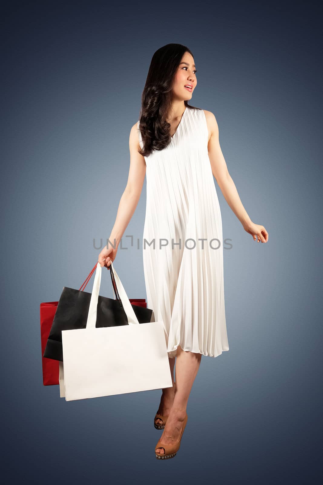 a happy women in white dress with a shopping bag on white background 