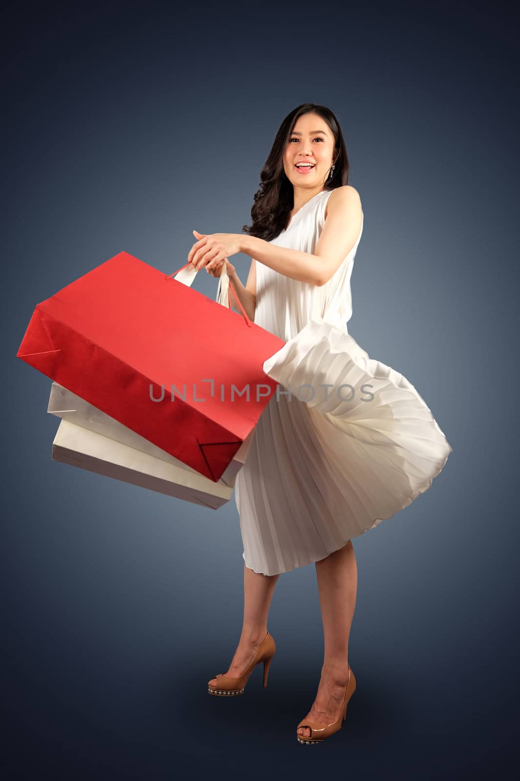a happy women with shopping bag on dark blue background  by Surasak