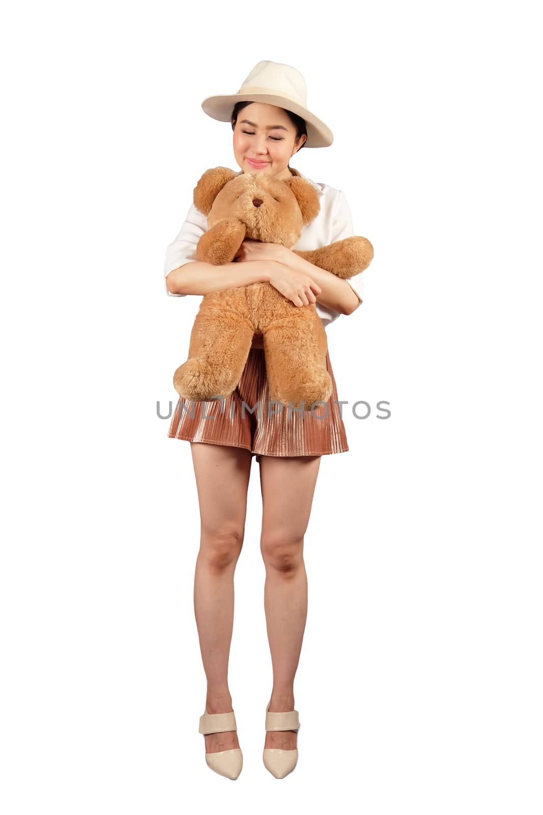 Lovely smiling young woman with hat holding big soft teddy bear  by Surasak