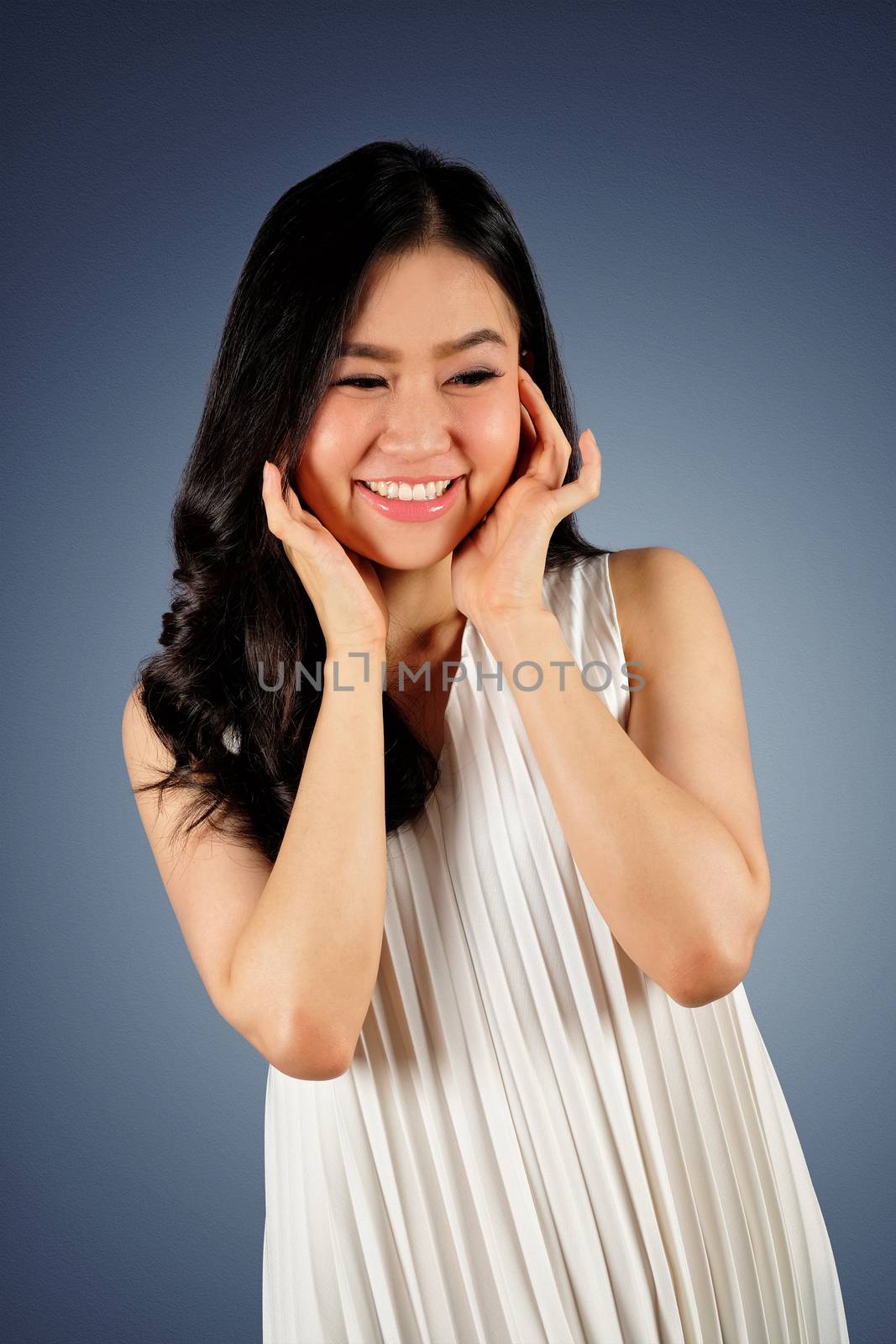 Happy woman wearing white dress looking at camera and dark blue background with clipping path