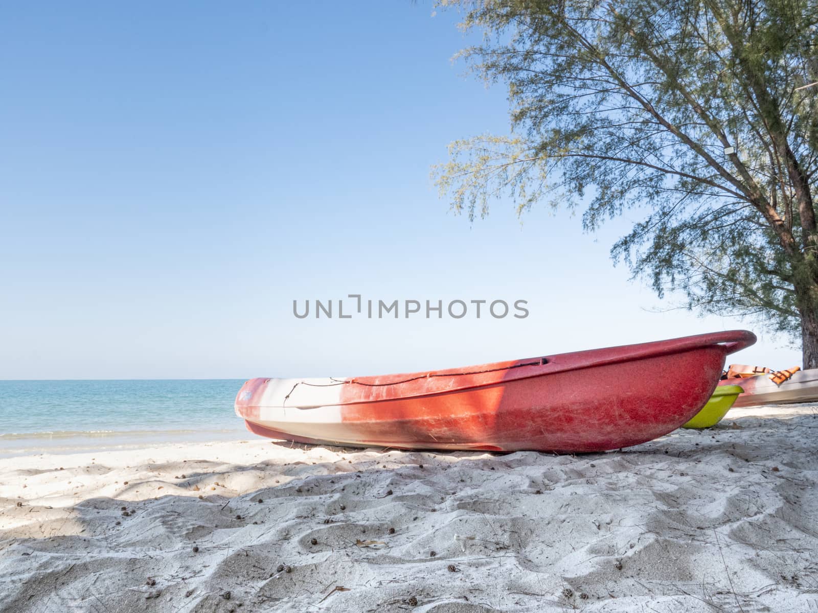 A red kayak on a beach.