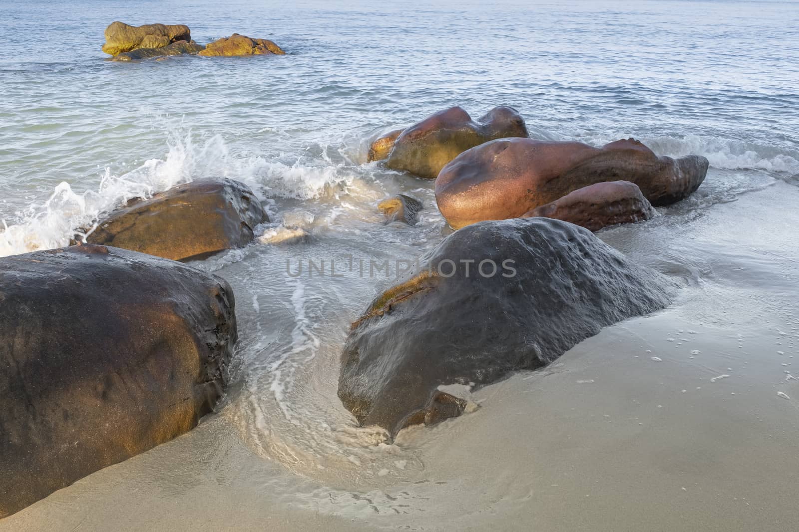 White waves splashing on the rocks at the sandy beach of the Gulf of Thailand.