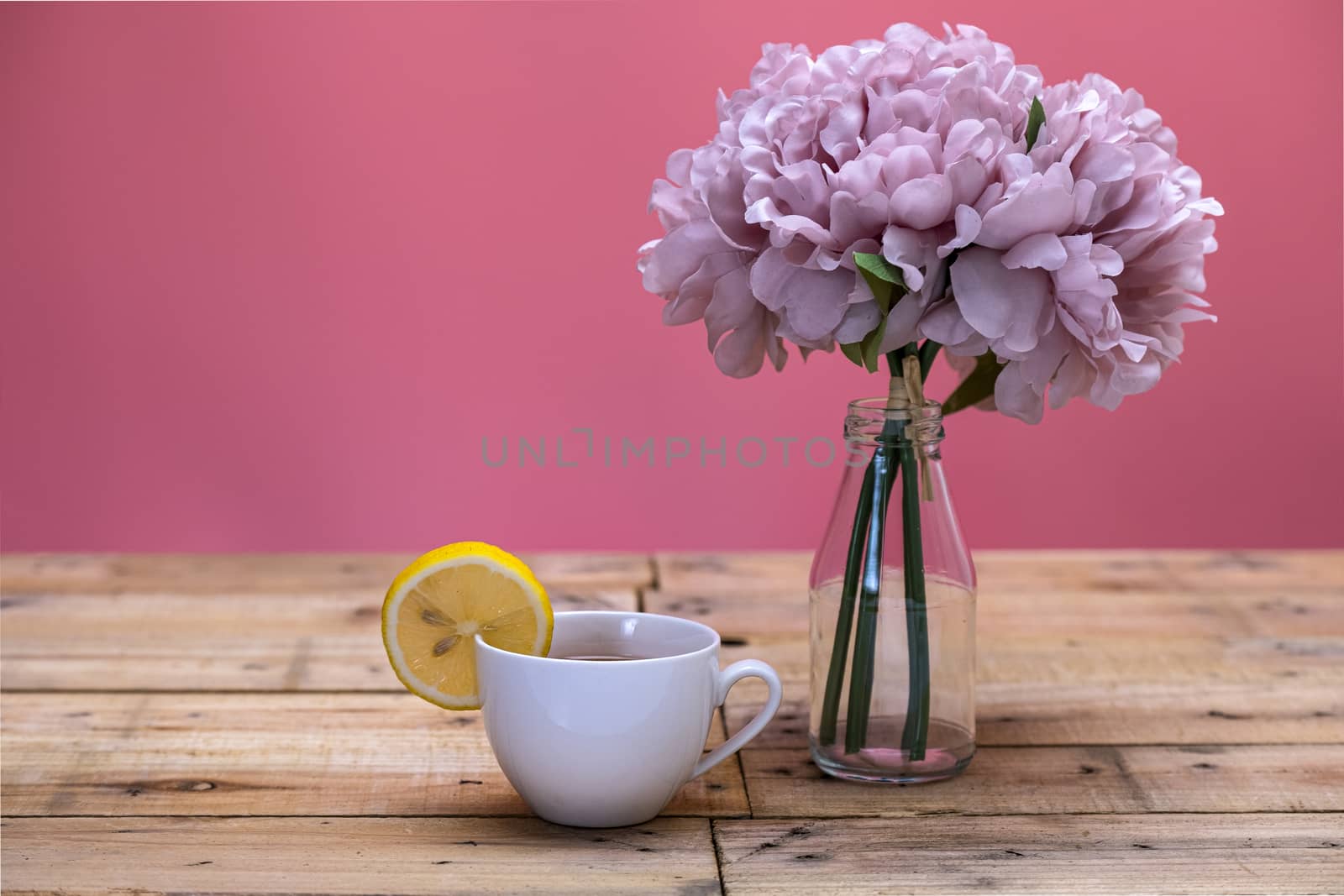 Lemon tea in white porcelein cup with lemon slice and wooden background.