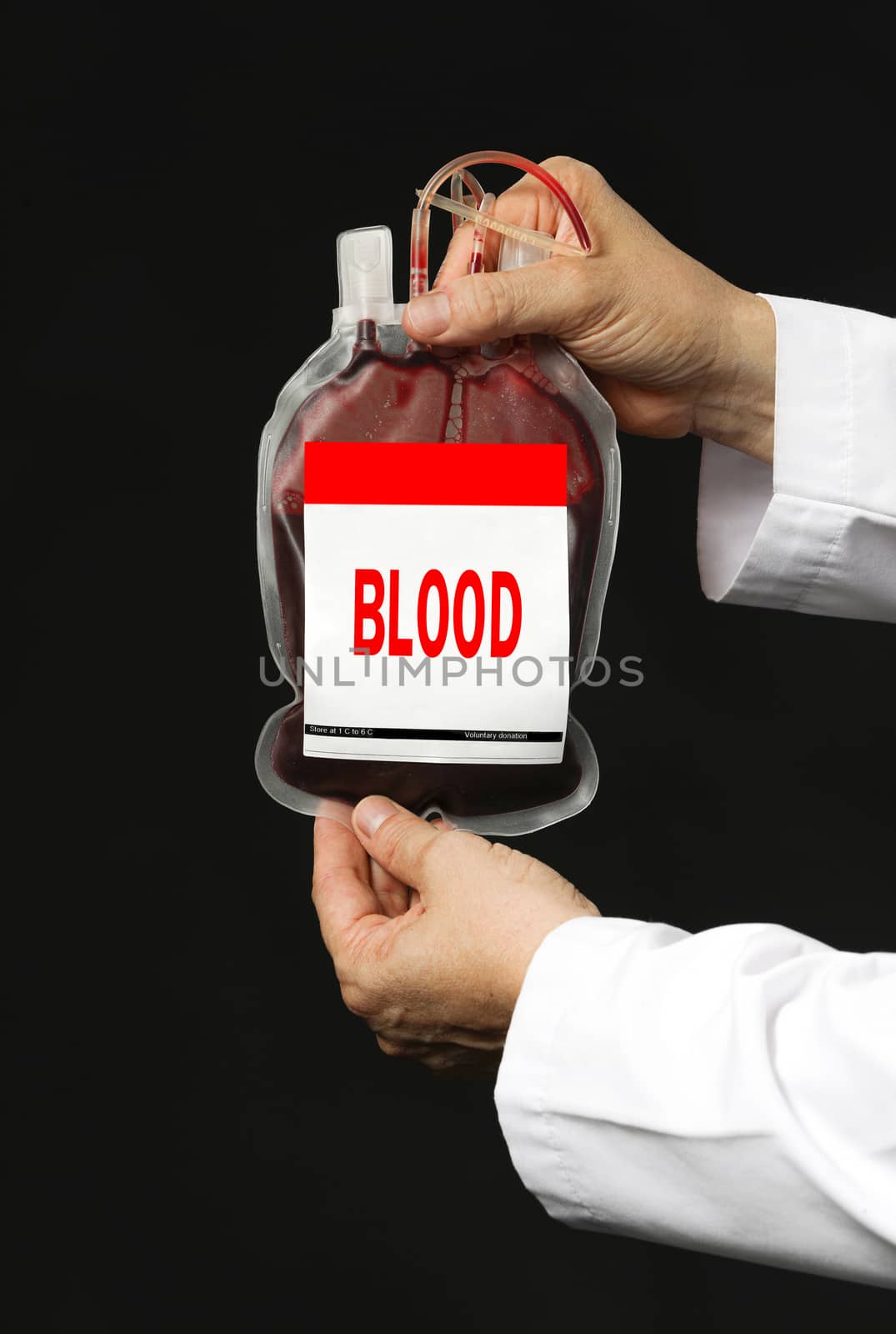 A man with white coat holding a blood transfusion bag. Isolated on dark background
