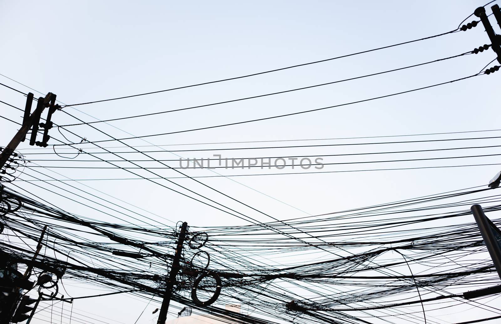 Messy electrical wires looking from street level on clear sky city background