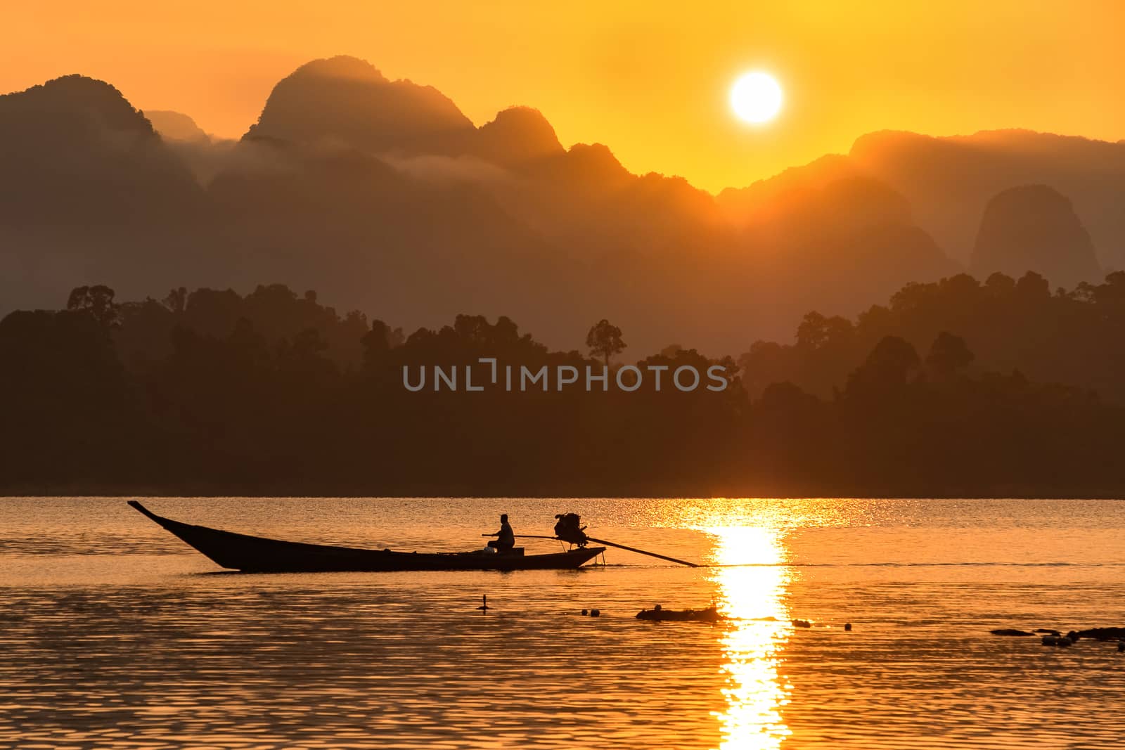 silhouette image of a  boat sailing in a dam in southern of Thailand in the morning.