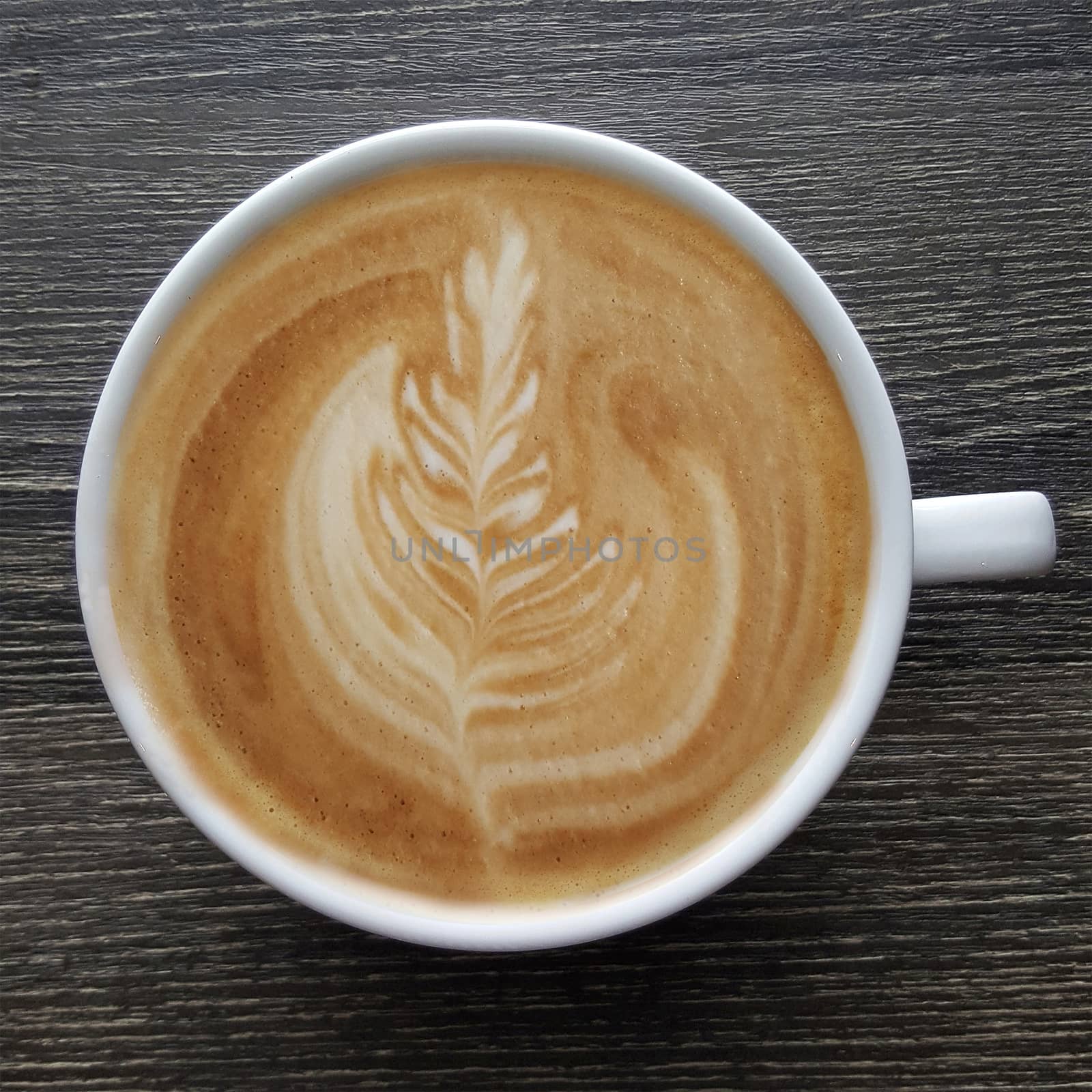 Top view of a mug of latte art coffee on timber background.