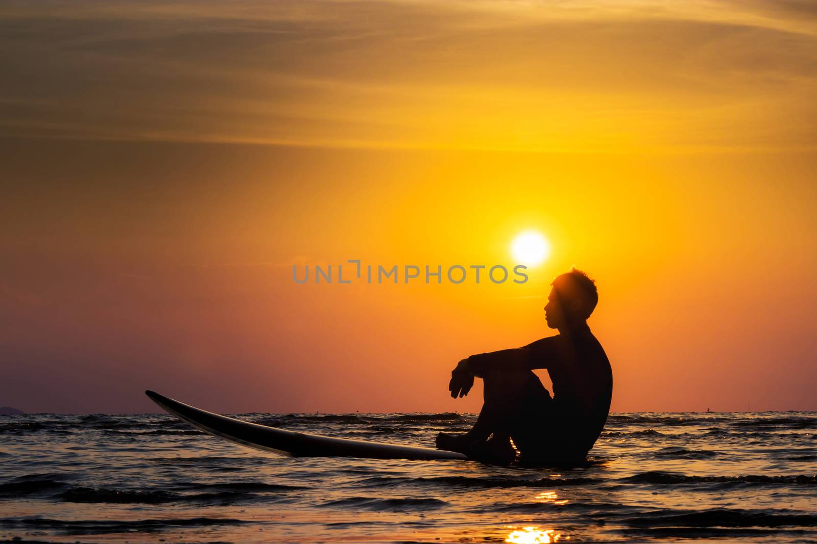 Silhouette of surf man sit on a surfboard. Surfing at sunset beach. Outdoor water sport adventure lifestyle.Summer activity. Handsome Asia male model in his 20s. by asiandelight