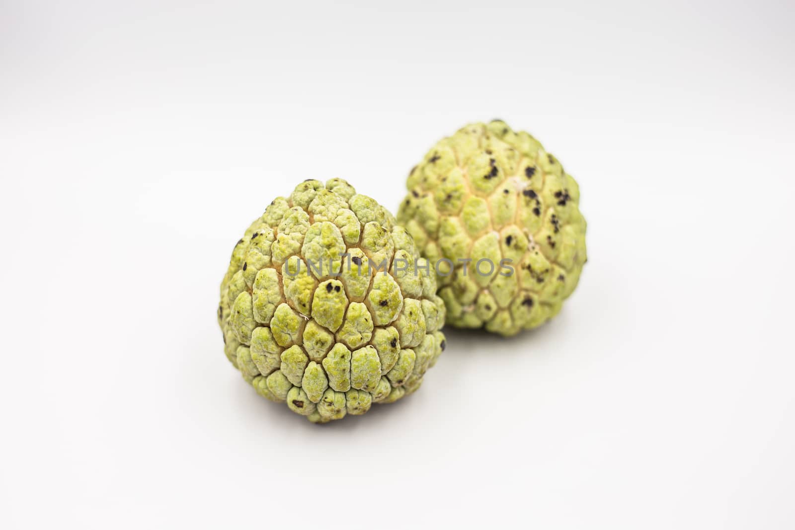 Two custard apples placed on a white ground.