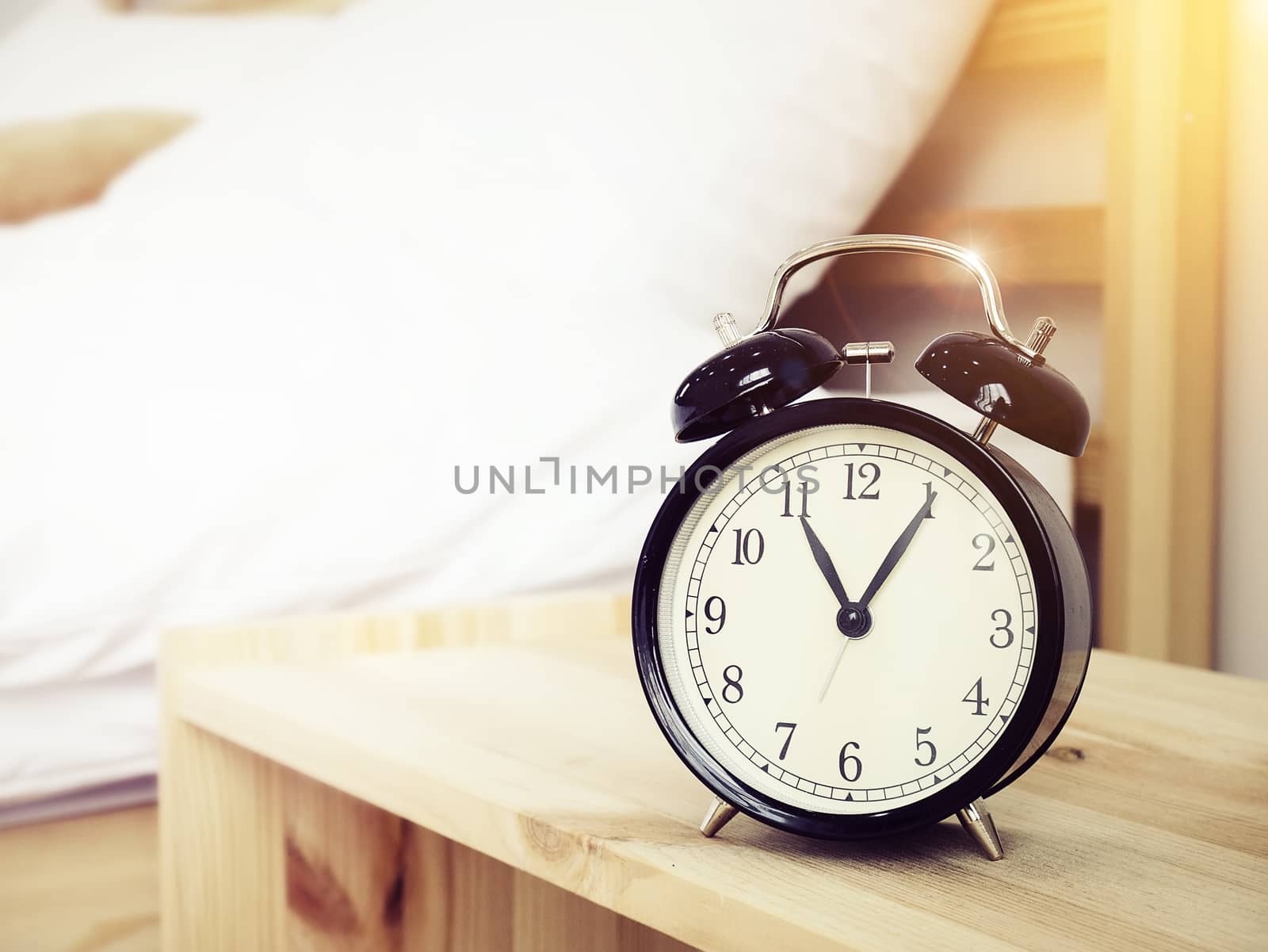 Closeup retro alarm clock on Bedside table with bed background and copy space, retro style