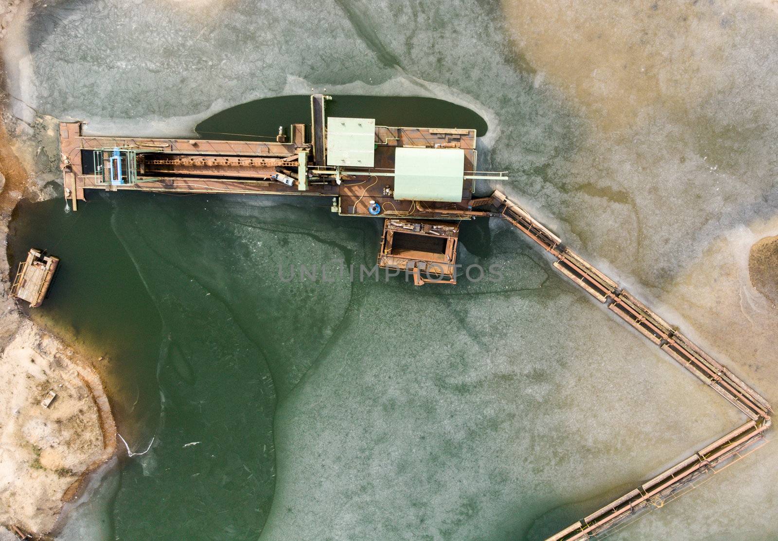 Vertical aerial photograph of the boom and suction dredger at the edge of the excavation area showing sand and the associated excavation pond, drone shot