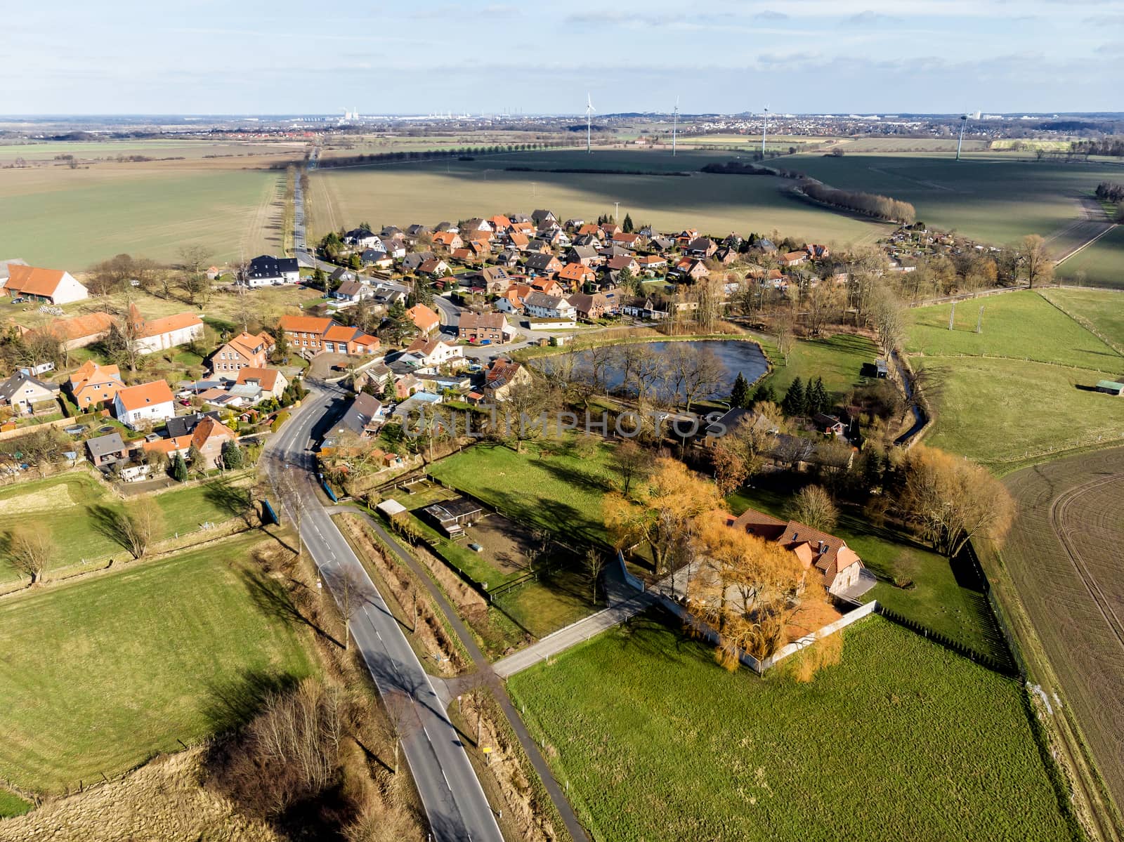 Aerial view of a village near Wolfsburg. With the main road in the foreground and a farm with a pond at the edge of the village. Made with drone