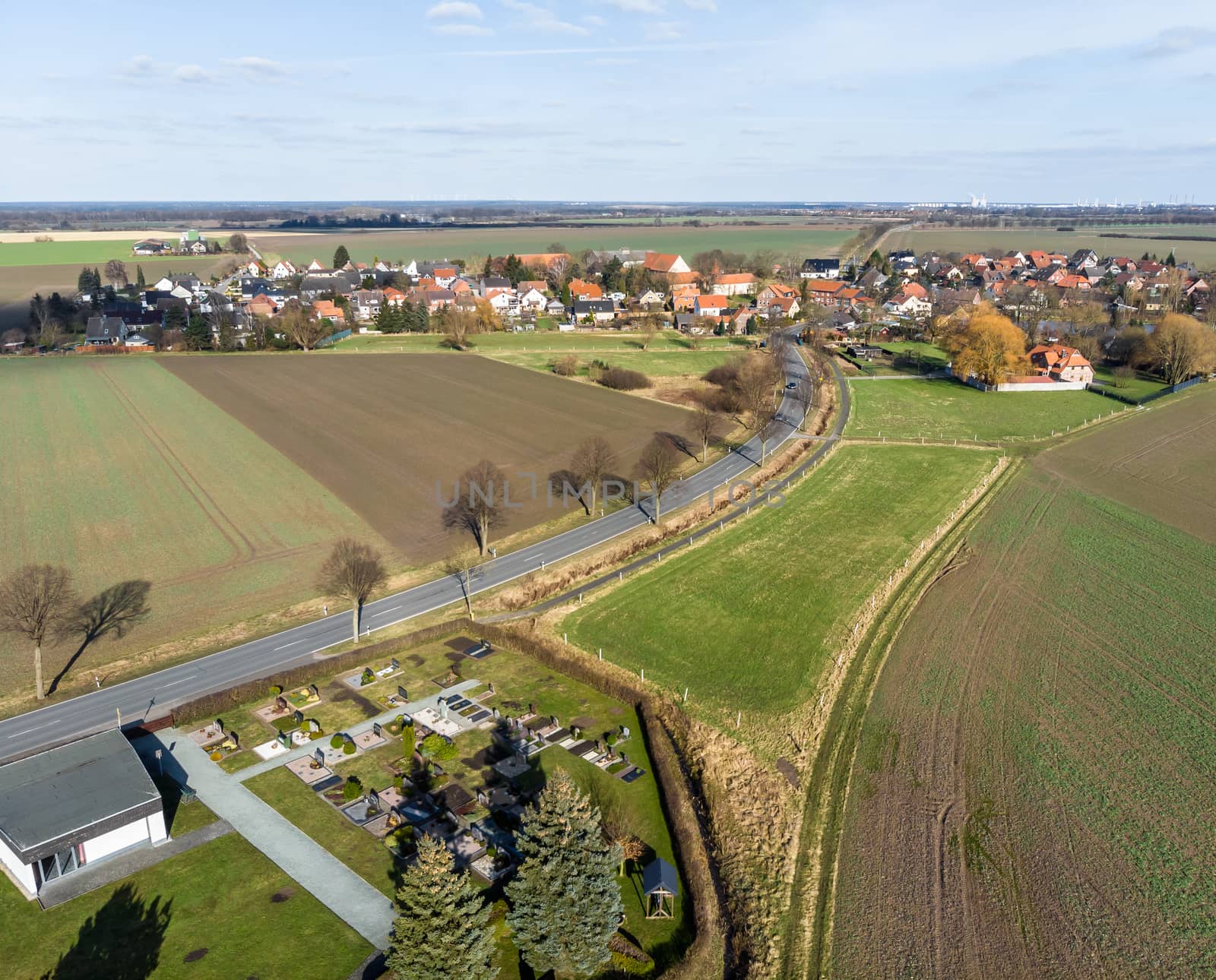 Aerial view of the access and transit road to a small village near Wolfsburg. With the village cemetery in the front corner of the aerial photograph. Made with drone