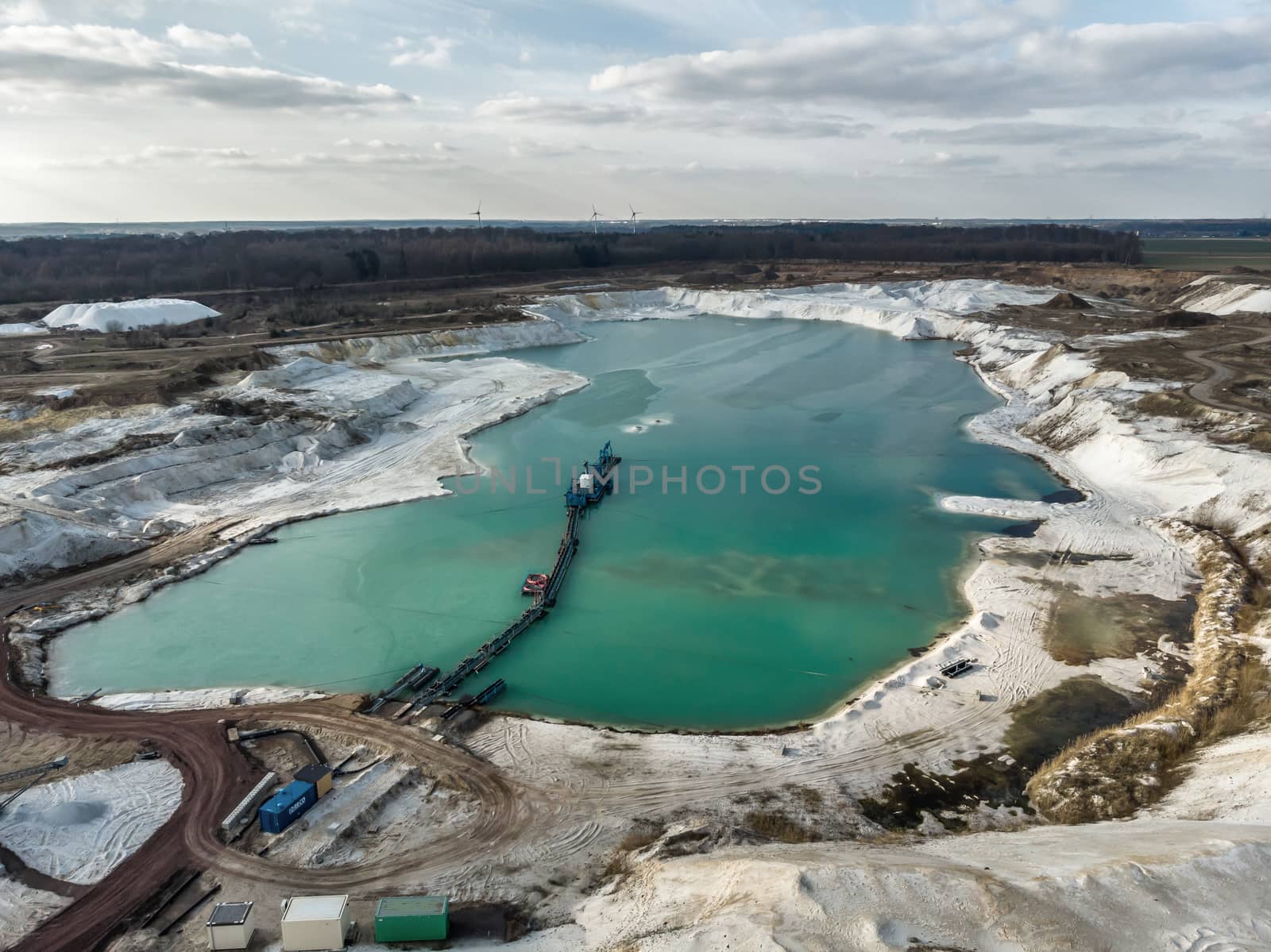 Aerial photo of one of the quartz quartz quartz quarry mining ponds with a suction dredger in the foreground and a dramatic sky. Made with drone