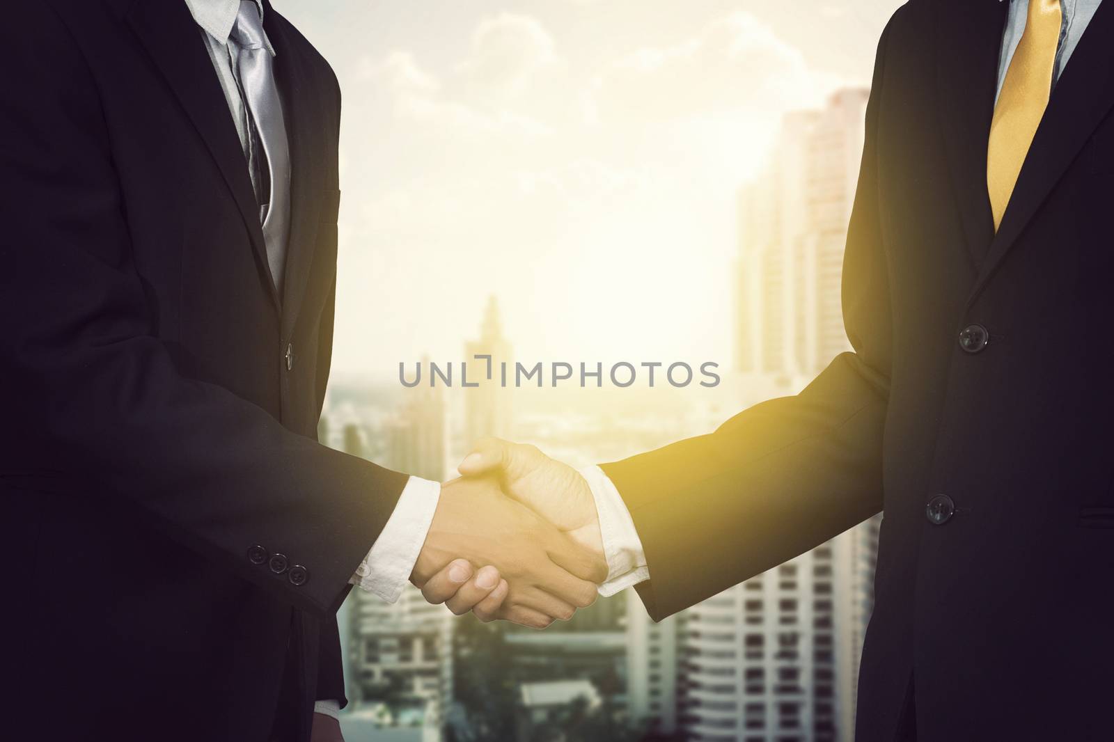 Two cheerful businessman shaking hands with city background, anonymous face by asiandelight