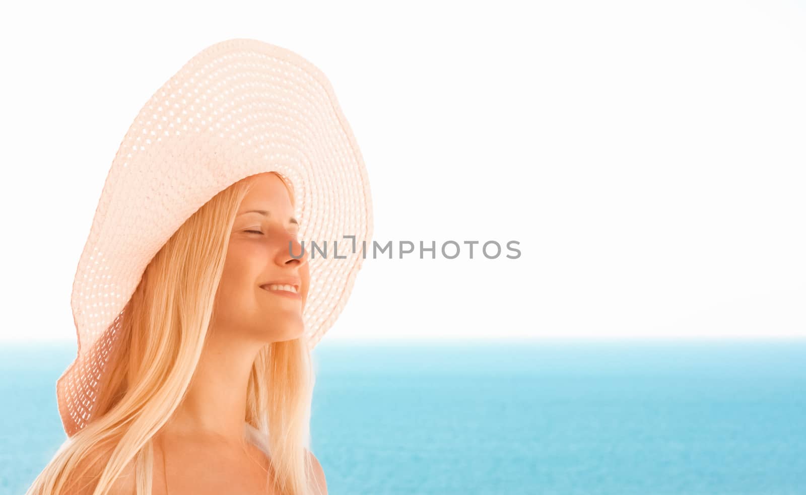 Woman with blond hair wearing hat, enjoying seaside and beach lifestyle in summertime, holiday travel and leisure concept