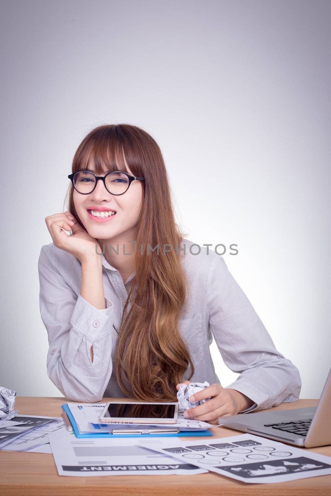 Happy Asian business woman leaning on the table in office with smiley face