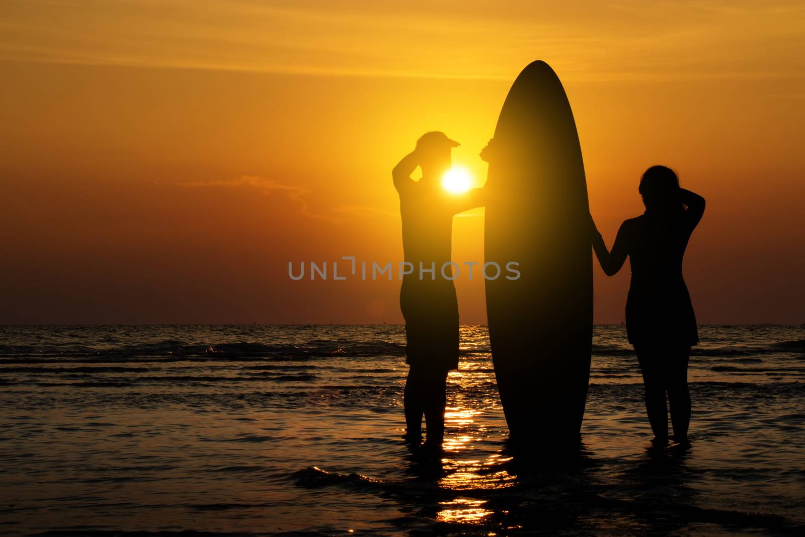Man and girl with surfboard on the beach at sunset by asiandelight