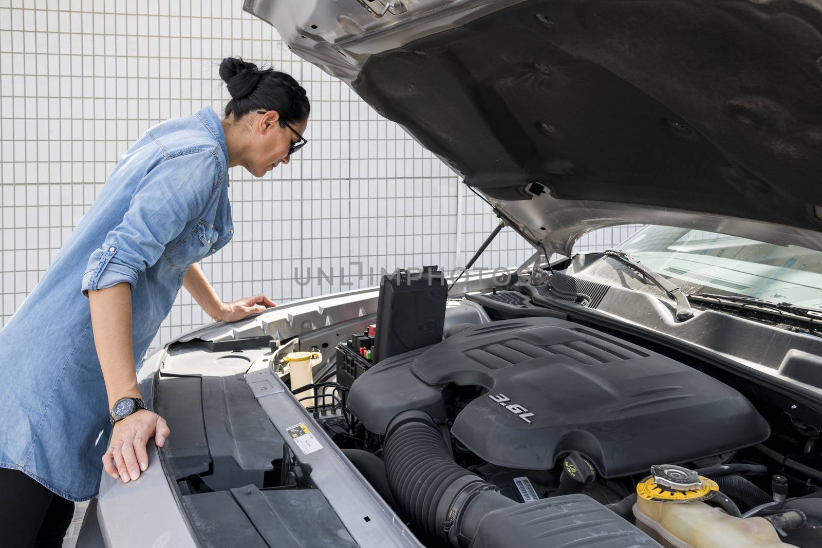 Woman looking at fuse box of her sport car