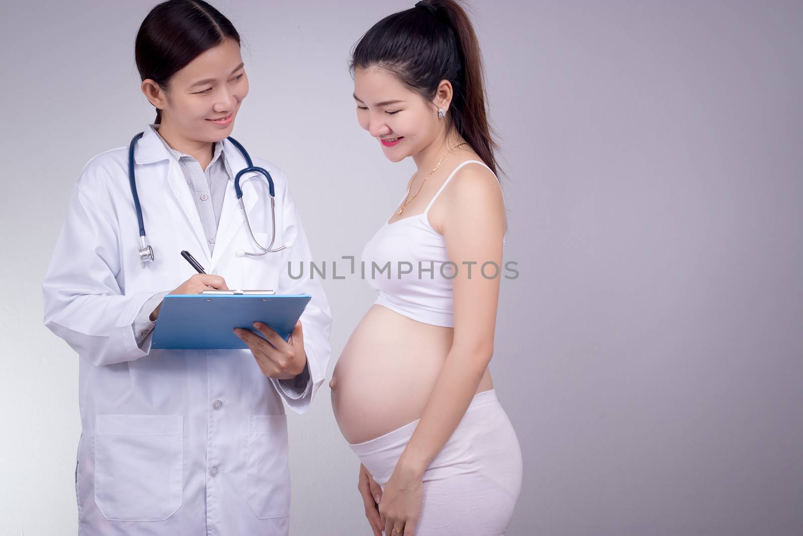Pregnancy, motherhood, people, medicine and fertility concept - happy pregnant woman with doctor at maternity hospital.