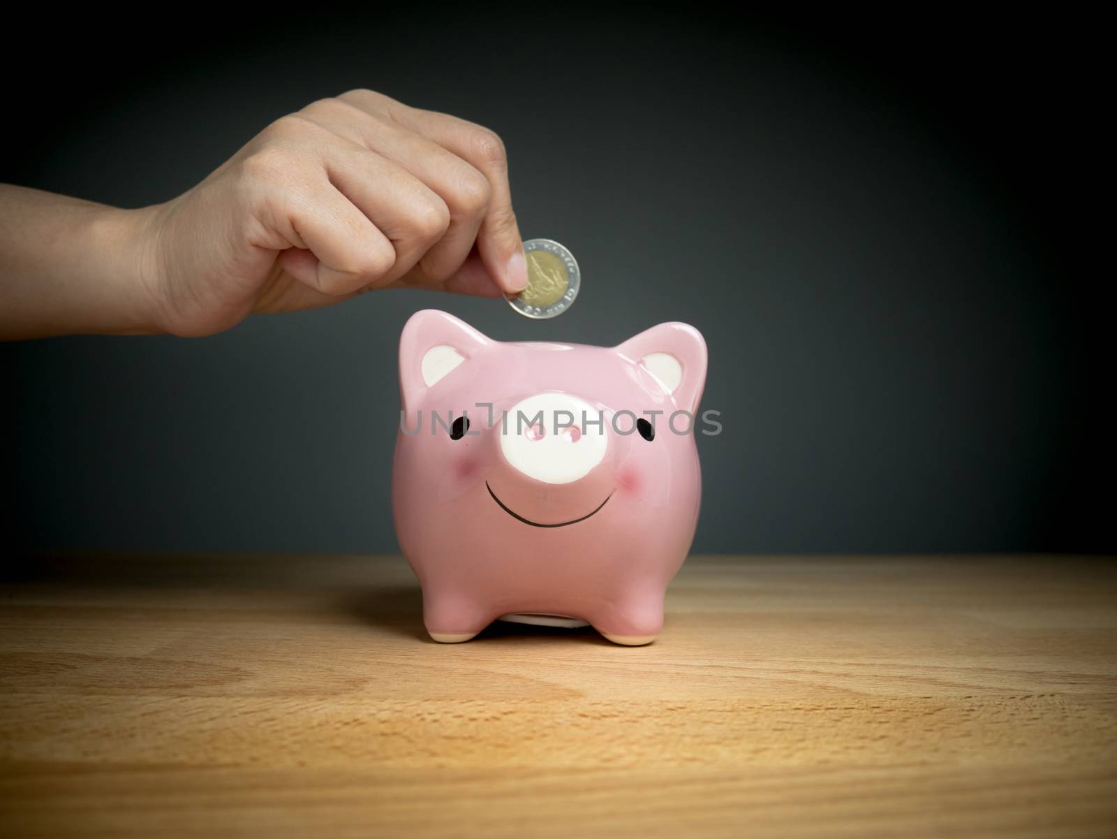 hand add coin to piggy bank save coin, time and money concept. by asiandelight