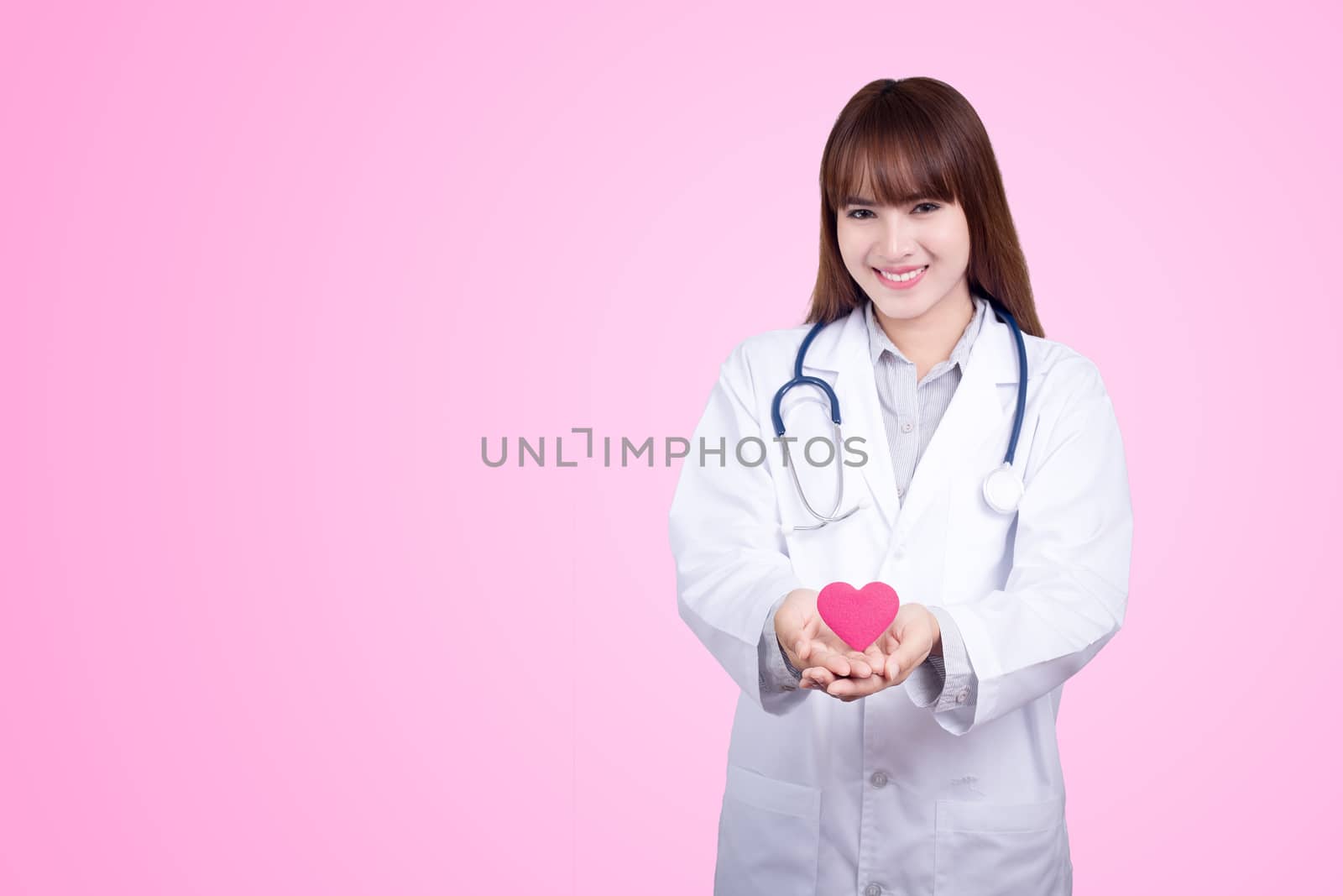 Healthy concept : Young Asian doctor with red heart in hand. Pink background
