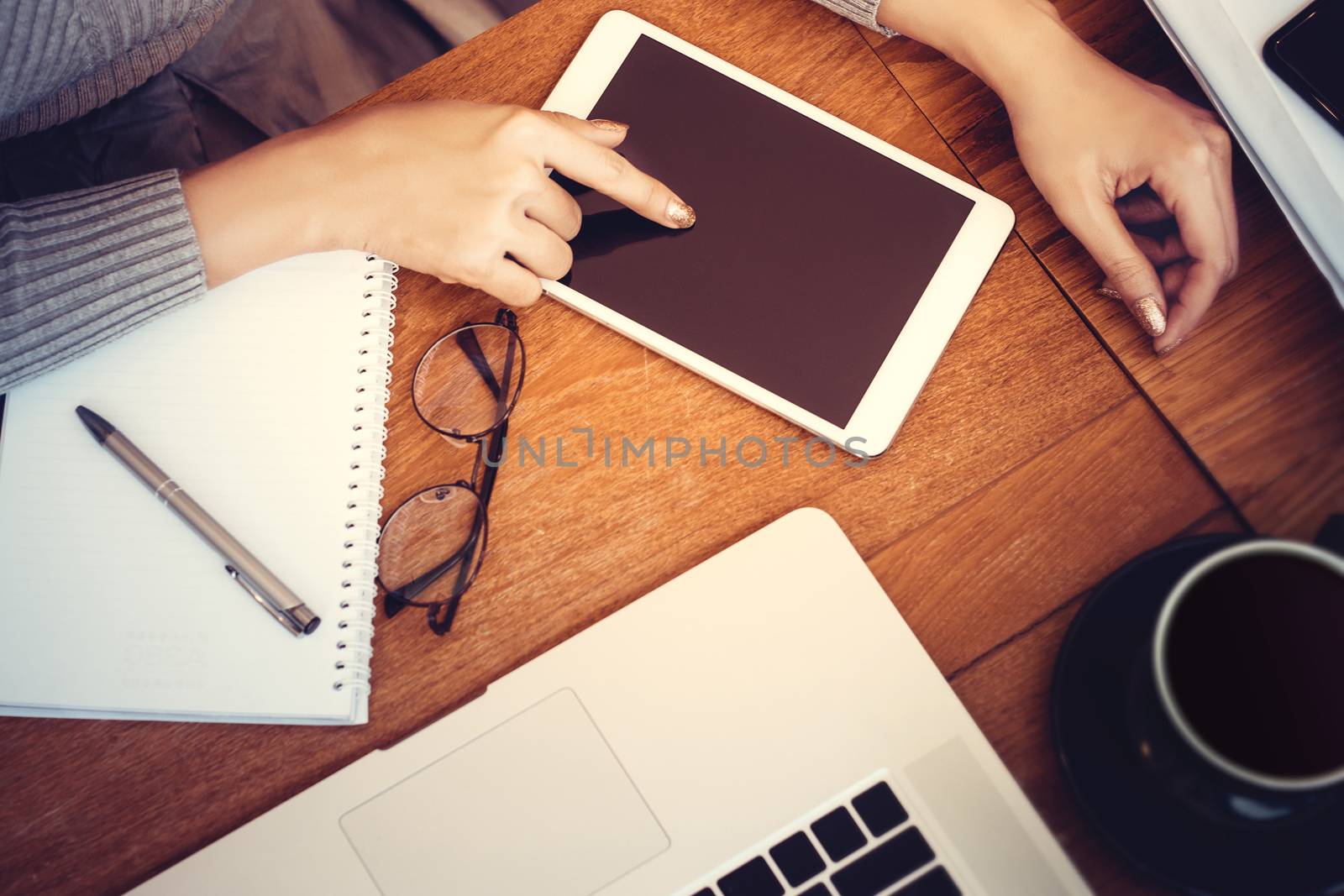 Technology concept: girl using a tablet with blank screen for copy space , hardwood desktop and stationery on background
