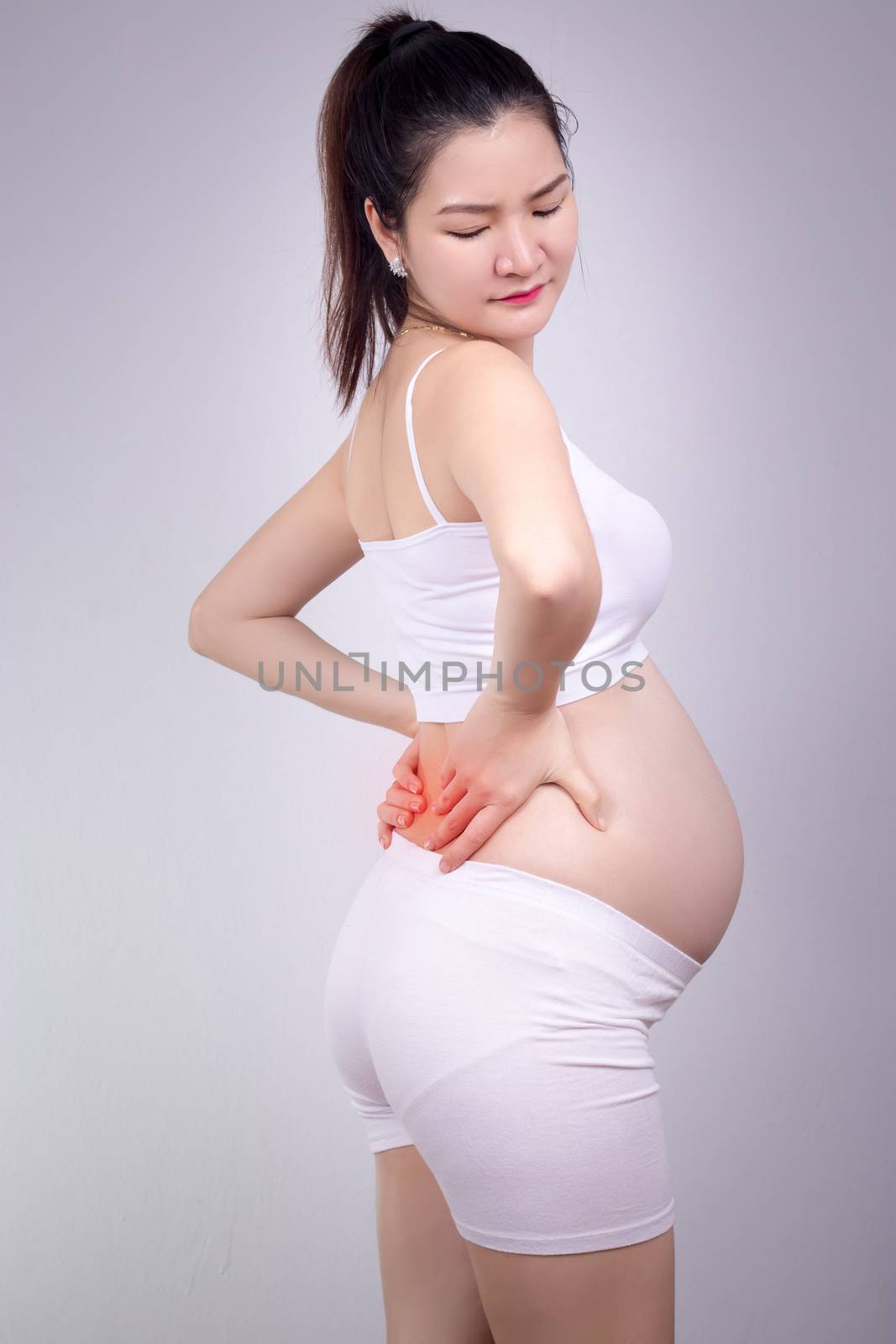 Pregnant healthy problem concept : Young Asian pregnant woman with a strong pain massaging her backache - pain in red by asiandelight