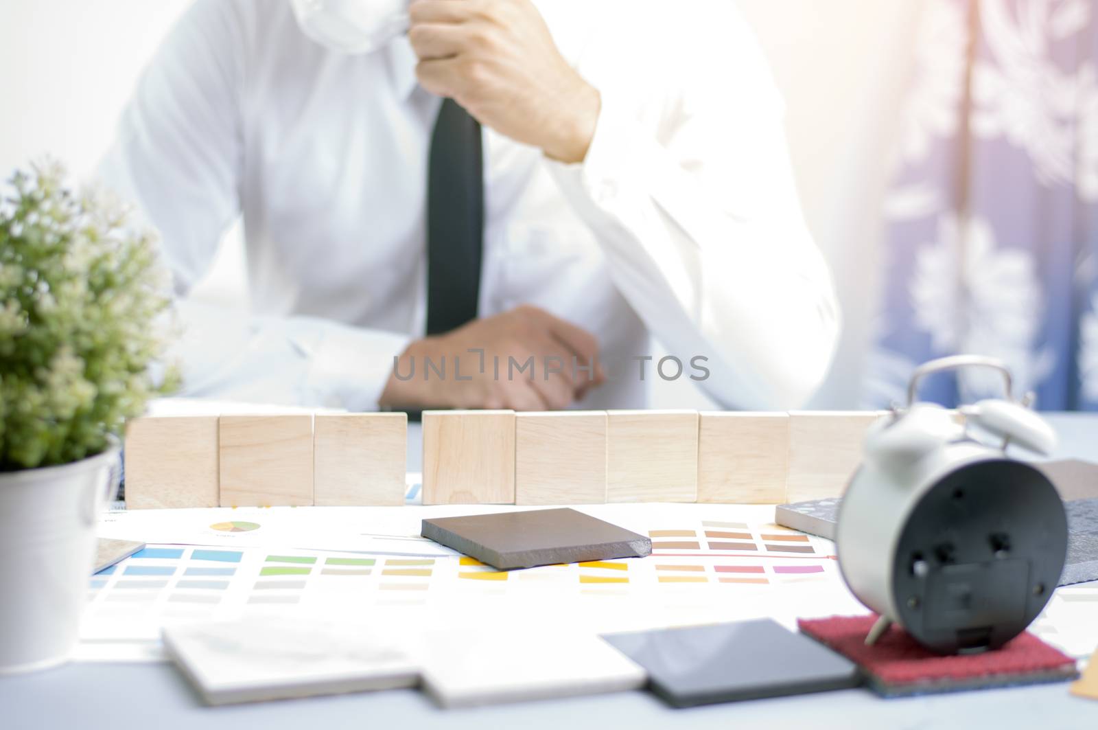 Wooden plate for text on the work table. Defocus man holding cup of coffee for background. Interior design concept. Materials design for home enovation.