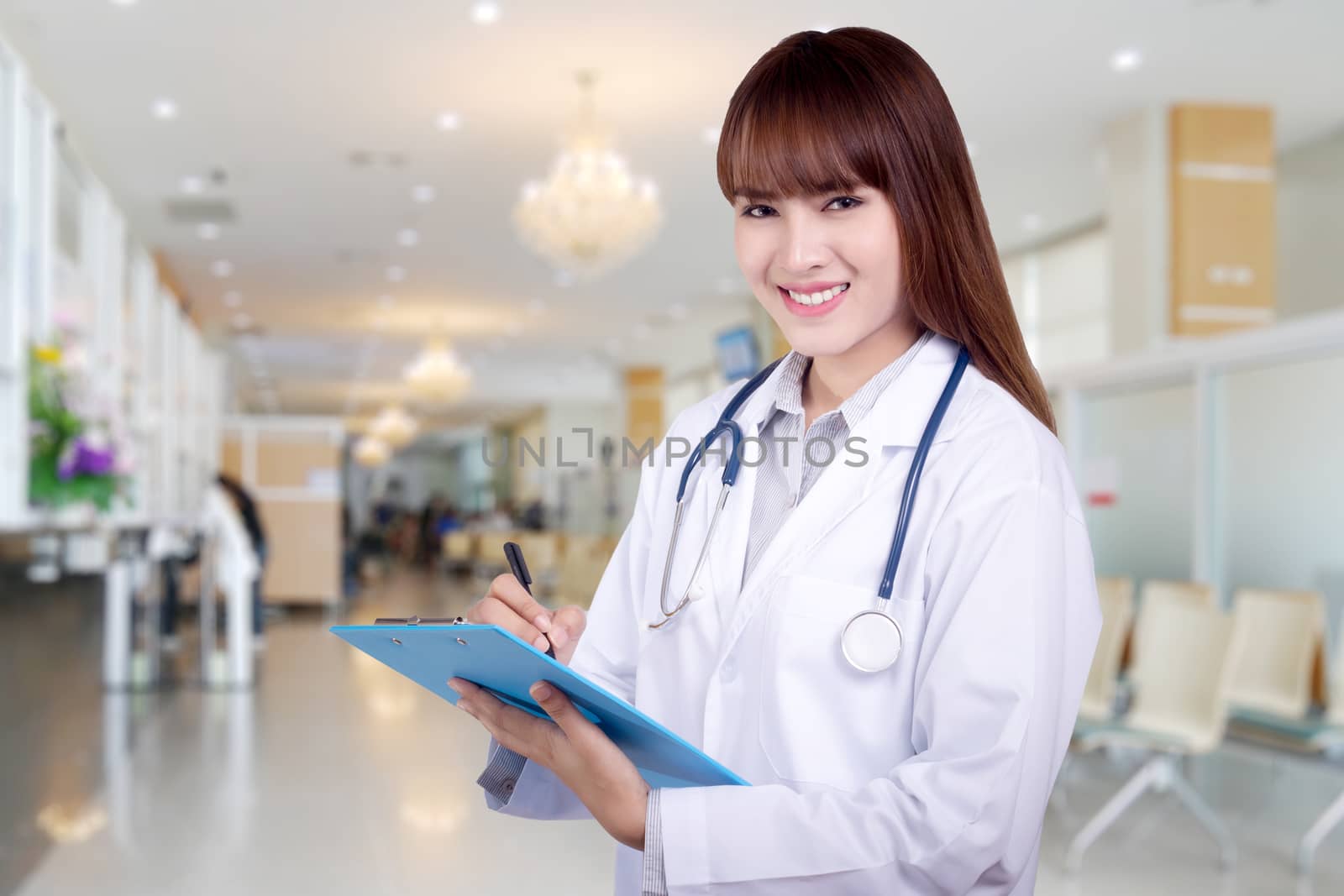 Detail of a young Asian woman doctor holding a clipboard standing on hospital background. health care concept by asiandelight