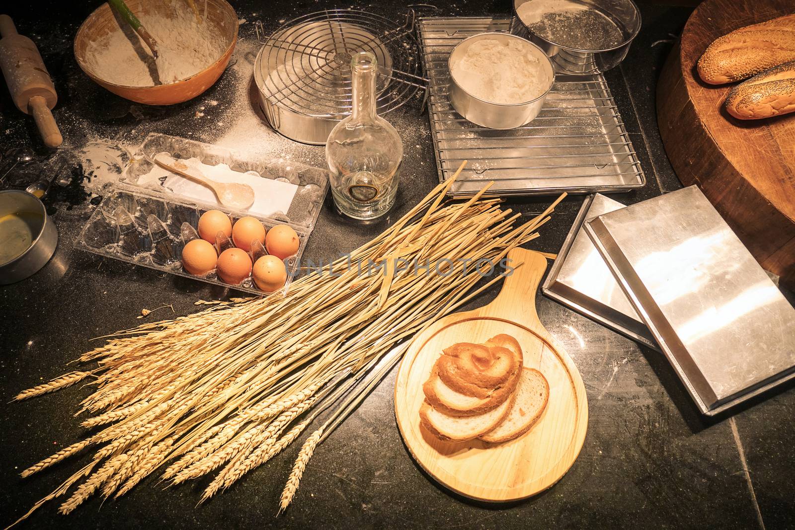 Cluttered kitchen by a beginner of homemade bakery with baking ingredients as flour, rolling pin, whisk, egg shells mesh, and plastic molds for baking. Pile the flour into a bowl with the egg yolk, top view