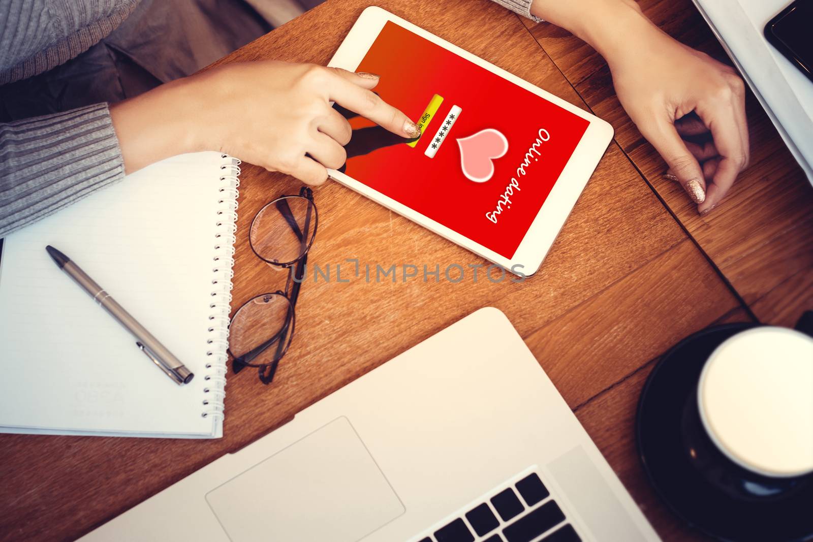 online love concept: girl using a digital generated tablet with dating site on the screen, hardwood desktop and stationery on background by asiandelight