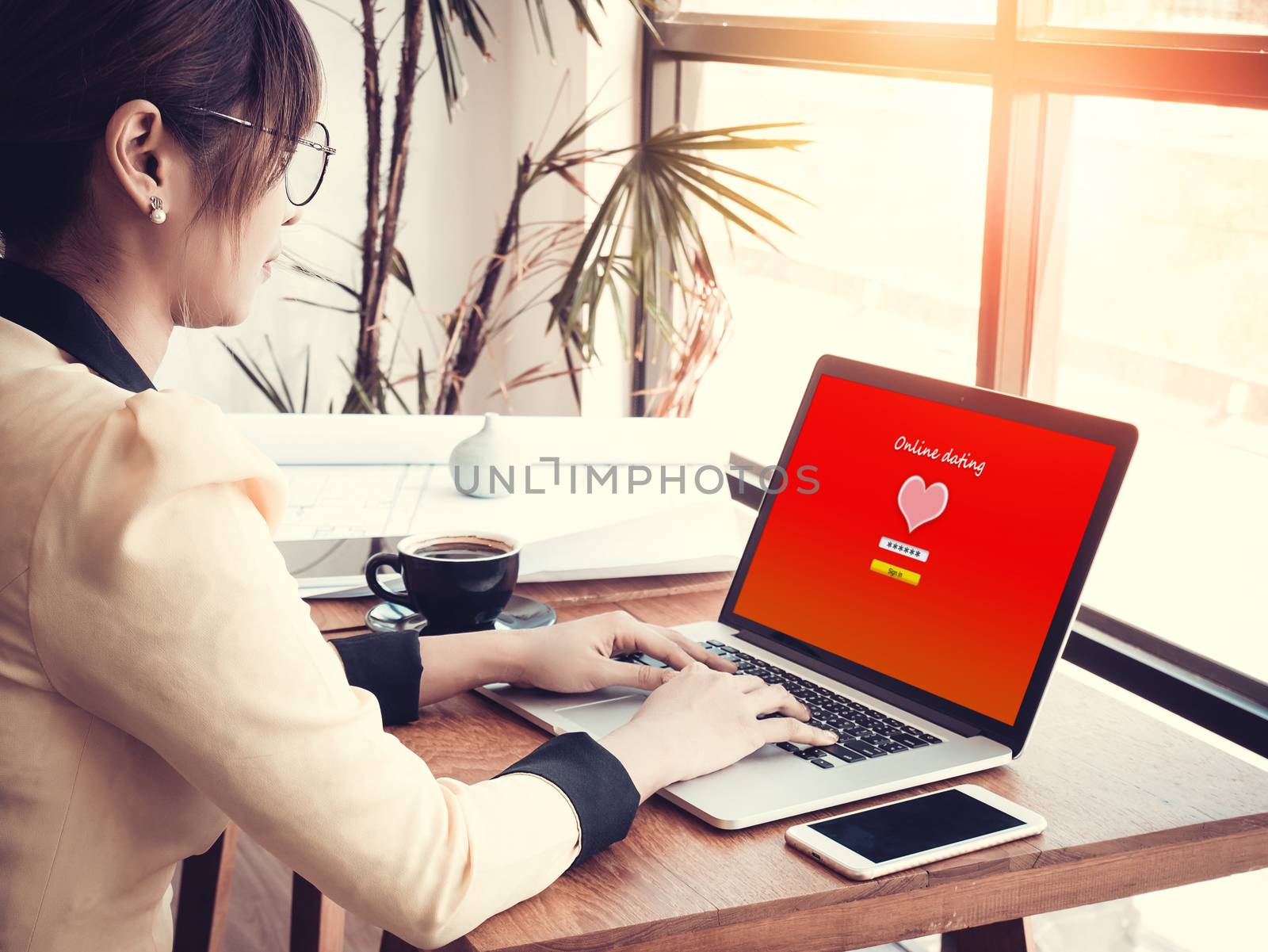 online love concept: office girl using online dating website on a laptop display, hardwood desktop and stationery on background
