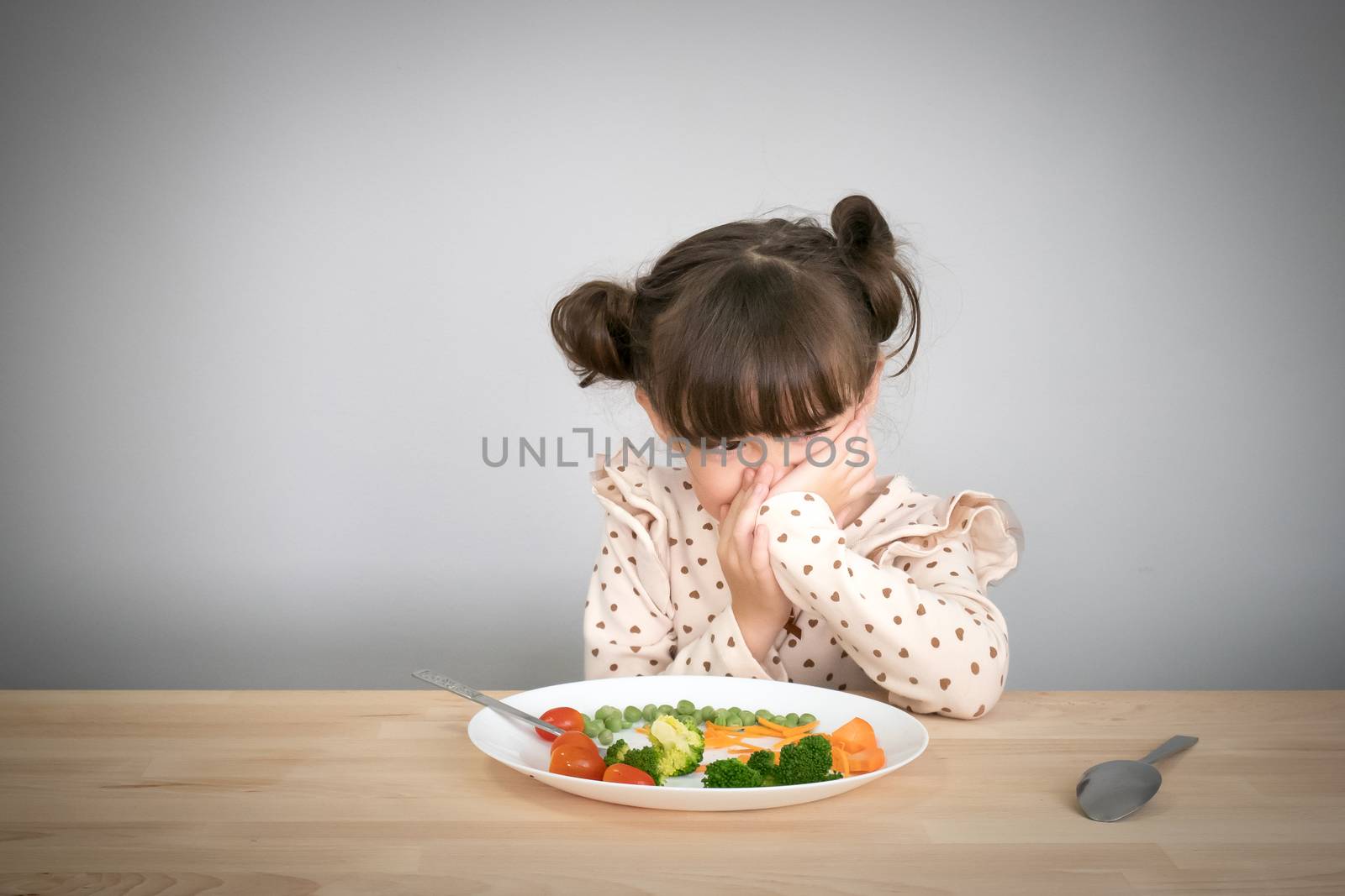 Nutrition & healthy eating habits for kids concept. Children do not like to eat vegetables. Little cute kid half race girl refuse to eat healthy vegetables. by asiandelight