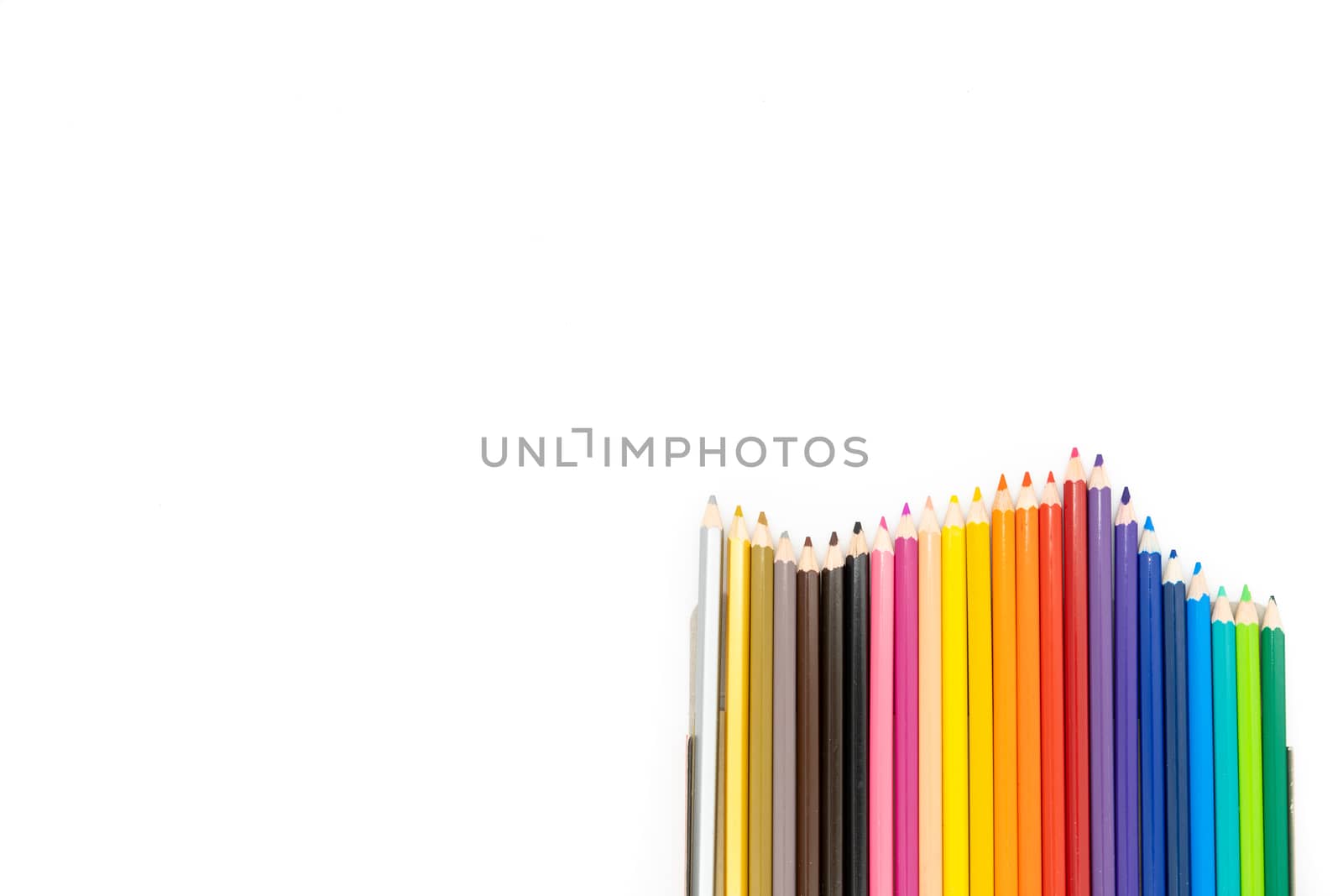 24 colored pencils arranged in waves in the bottom right corner of the picture on a white background
