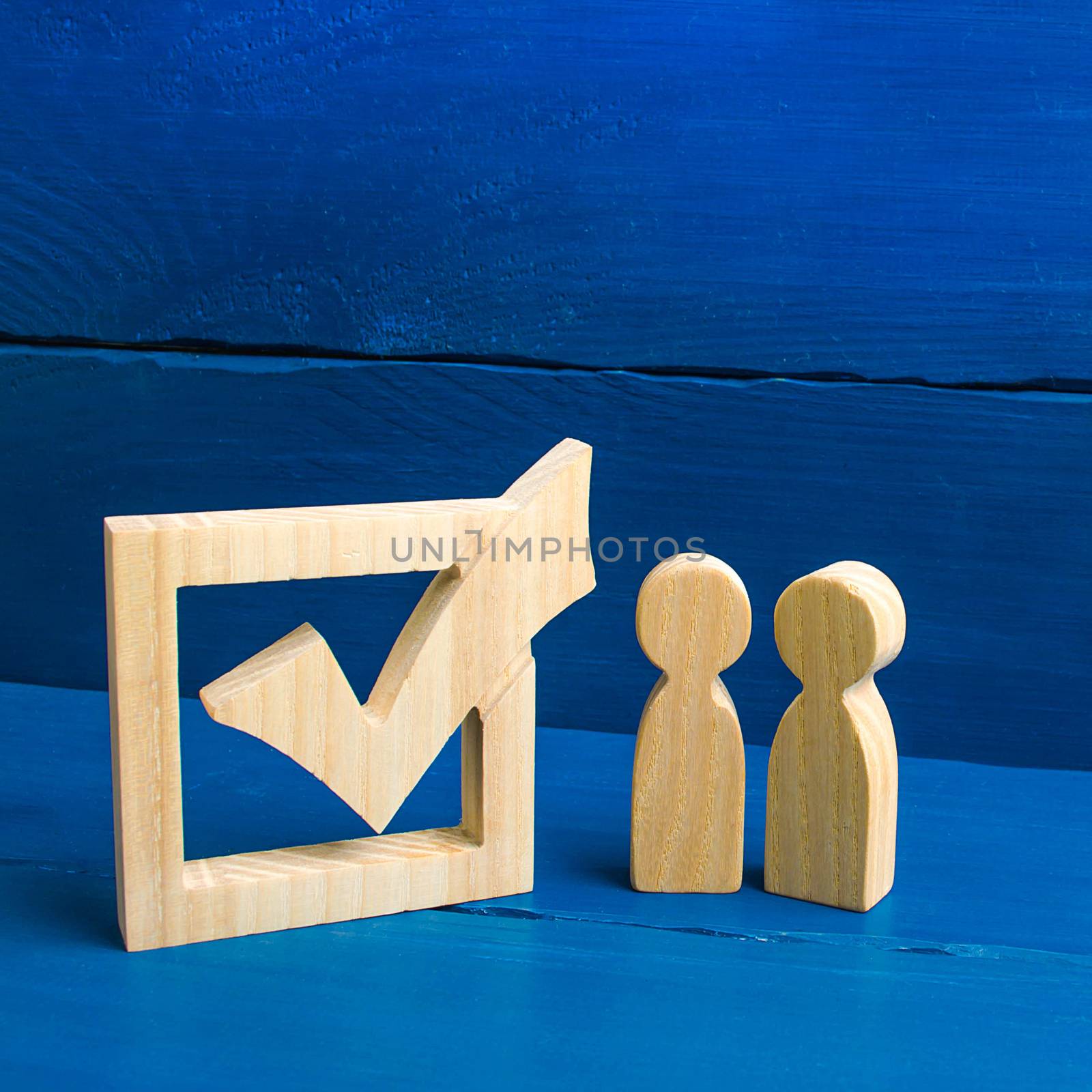 Two figures stand together next to tick in the box. The concept of elections and social technologies. Volunteers, parties, candidates, constituency electorates. Selective focus by iLixe48