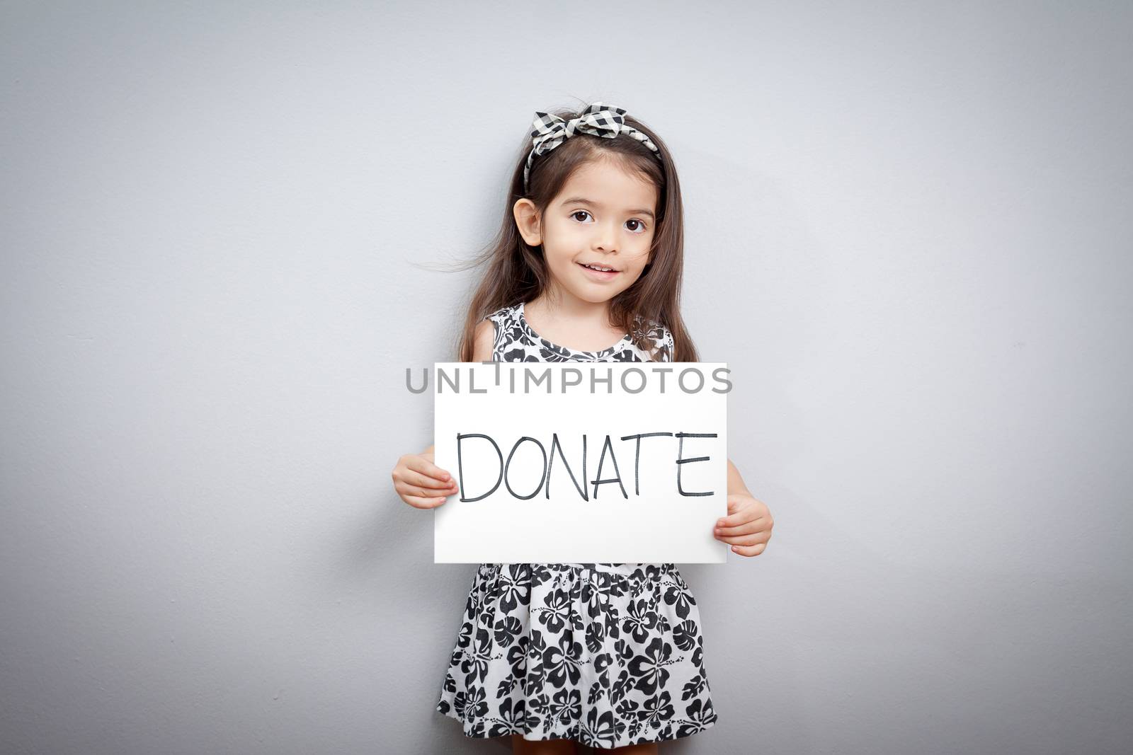 little cute girl with handwriting text donations on white paper. helping, giving , donate and donation concept