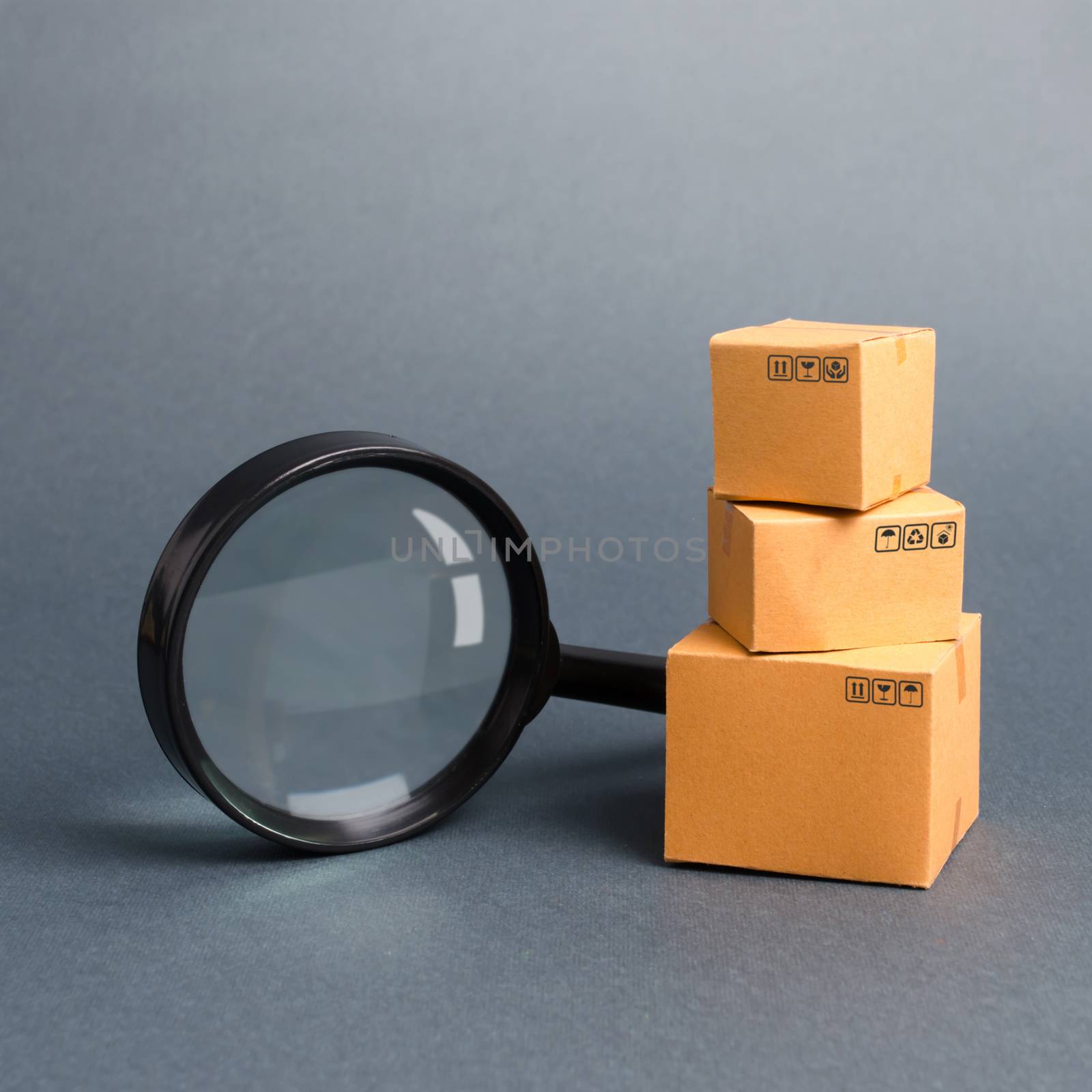 Cardboard boxes and a magnifying glass. Warehouse of finished products and equipment. buying and selling goods and services, internet commerce, online shopping, trade and turnover. Import and export by iLixe48