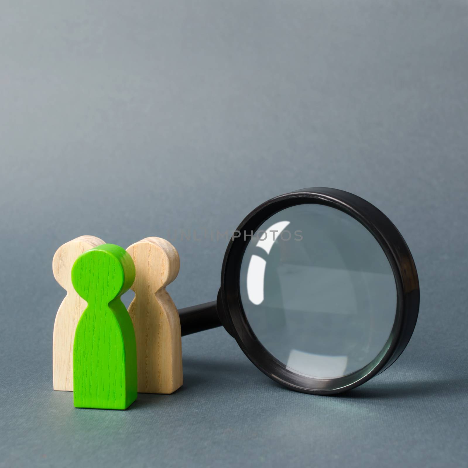 Three wooden human figure stands near a magnifying glass on a gray background. The concept of the search for people and workers. Search for vacancies and work. Human resources, management. by iLixe48