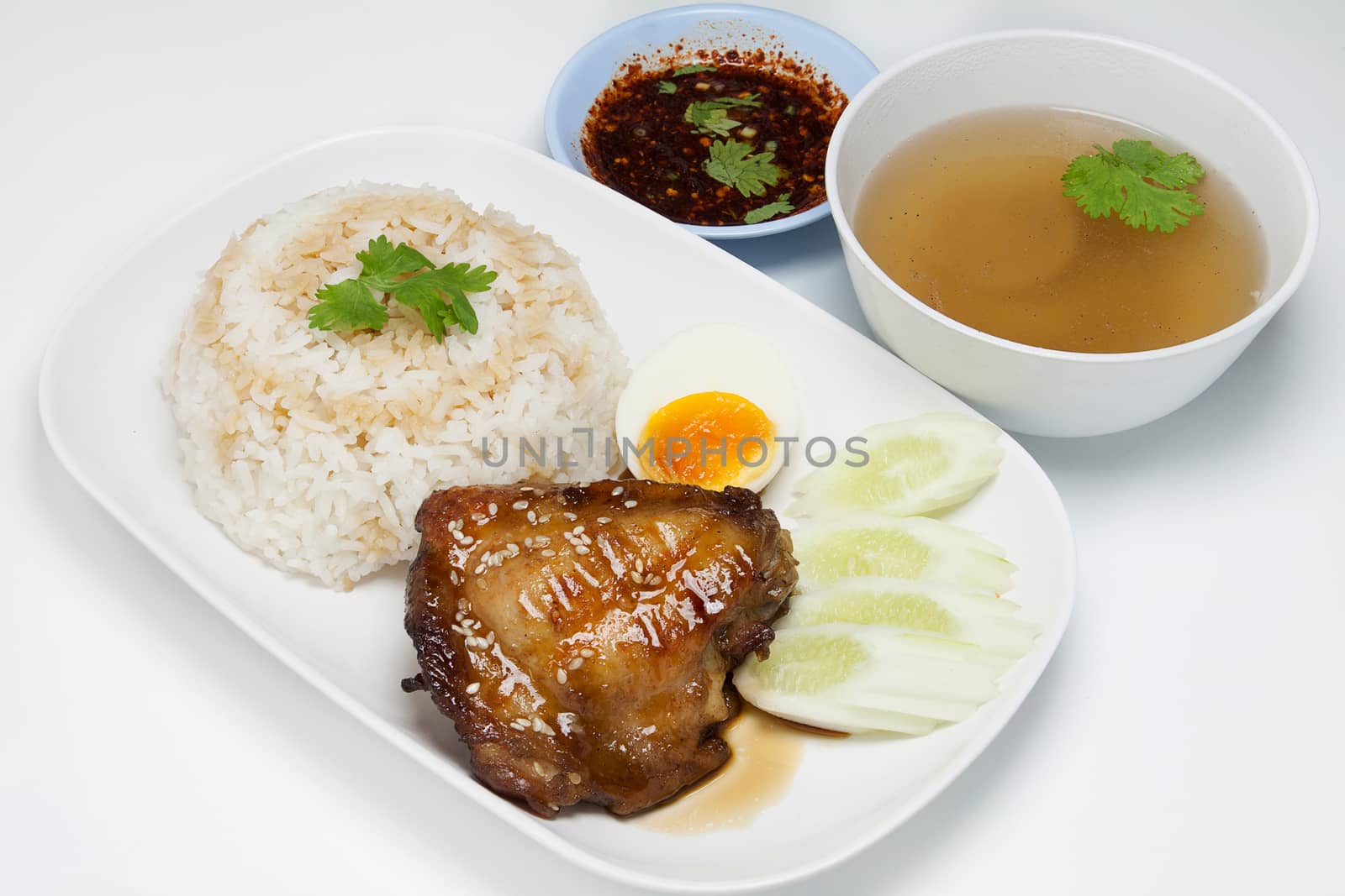 rice topping grilled chicken with teriyaki sauce , egg , cucumber , coriander, soup and spicy sauce  isolated on white background