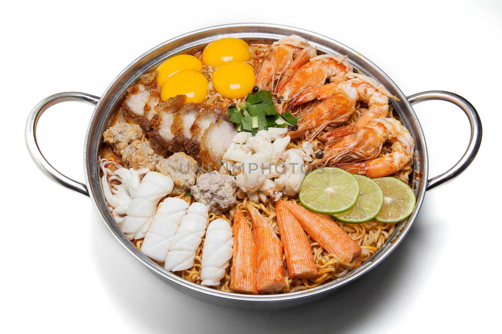 Pot of spicy instant noodles isolated on white background. Topping with eggs, lemon, pork , crispy pork, sausage , shrimp, squid, crab and coriander
